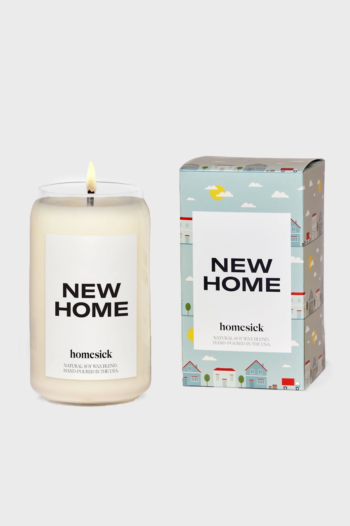 A Homesick Candles "New Home" candle sits beside its box, both featuring house and cloud illustrations—perfect as a home fragrance or a thoughtful housewarming gift.