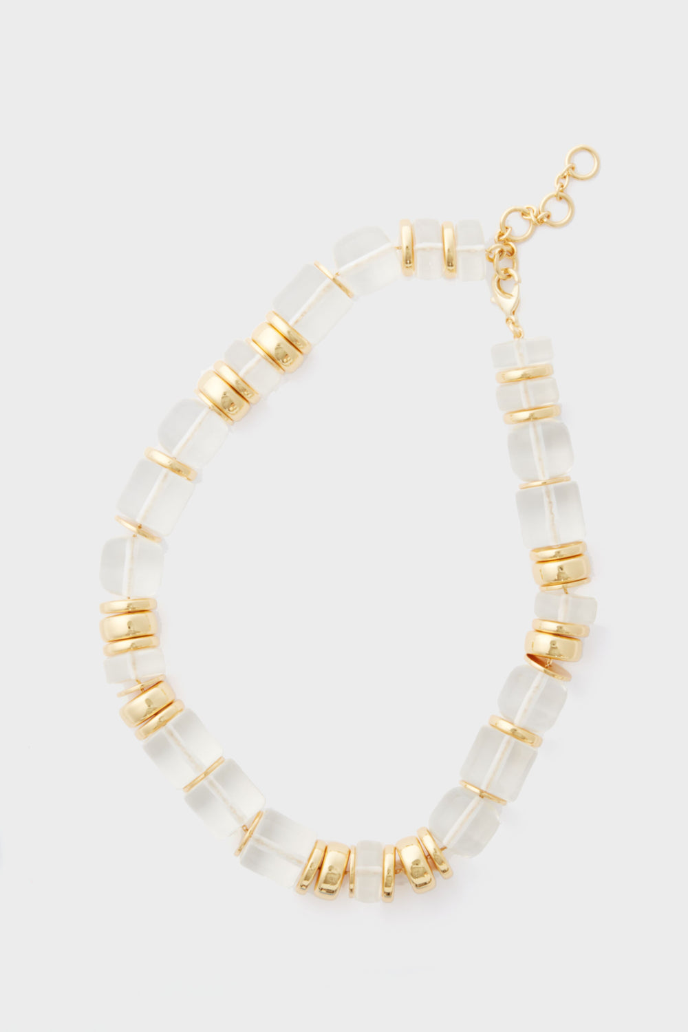 The Sadie Necklace by Tuckernuck Jewelry features translucent rectangular beads, gold round spacers, a gold clasp, and adjustable chain—an elegant statement piece with gold and clear beads for a timeless look.