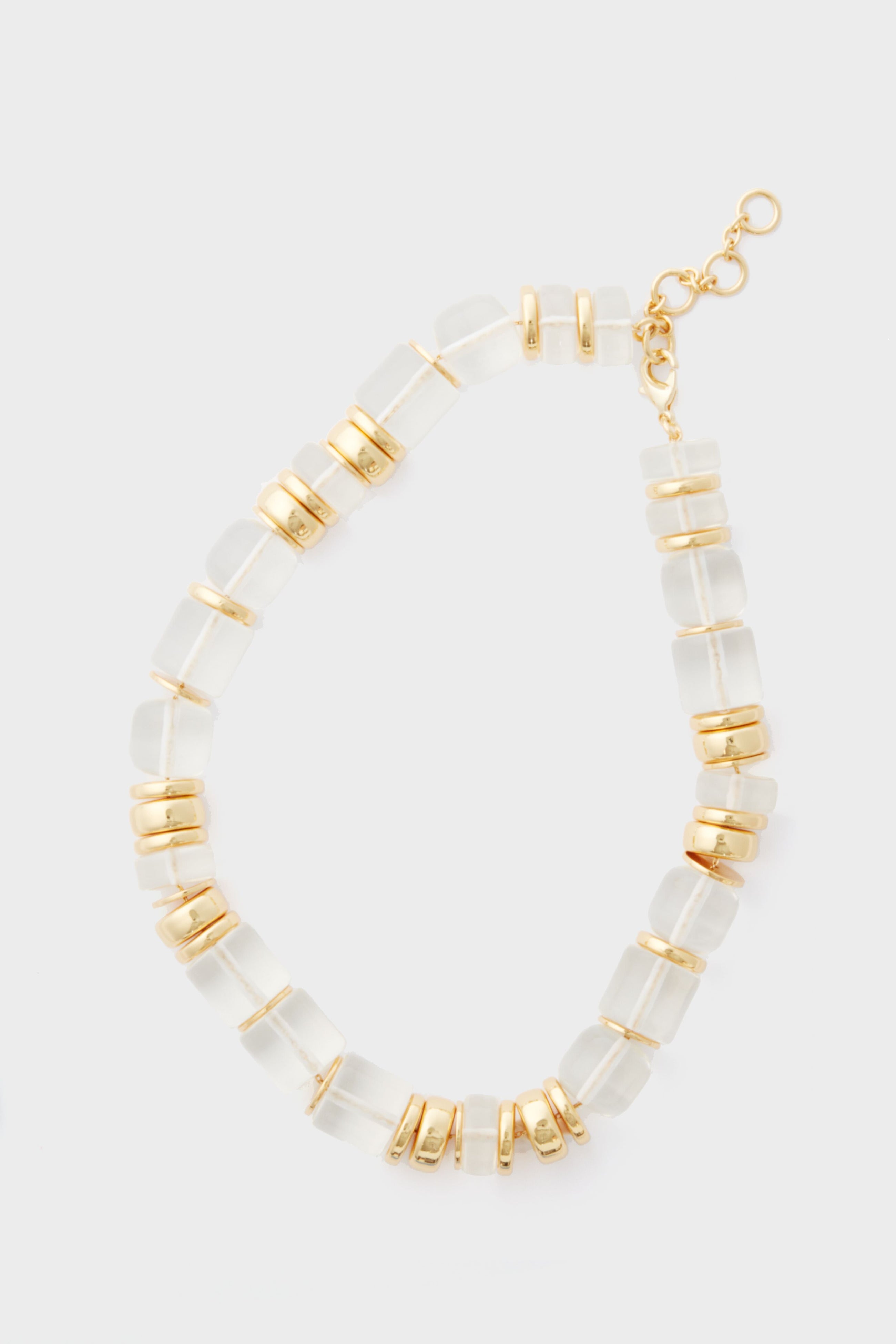 The Sadie Necklace by Tuckernuck Jewelry features translucent rectangular beads, gold round spacers, a gold clasp, and adjustable chain—an elegant statement piece with gold and clear beads for a timeless look.