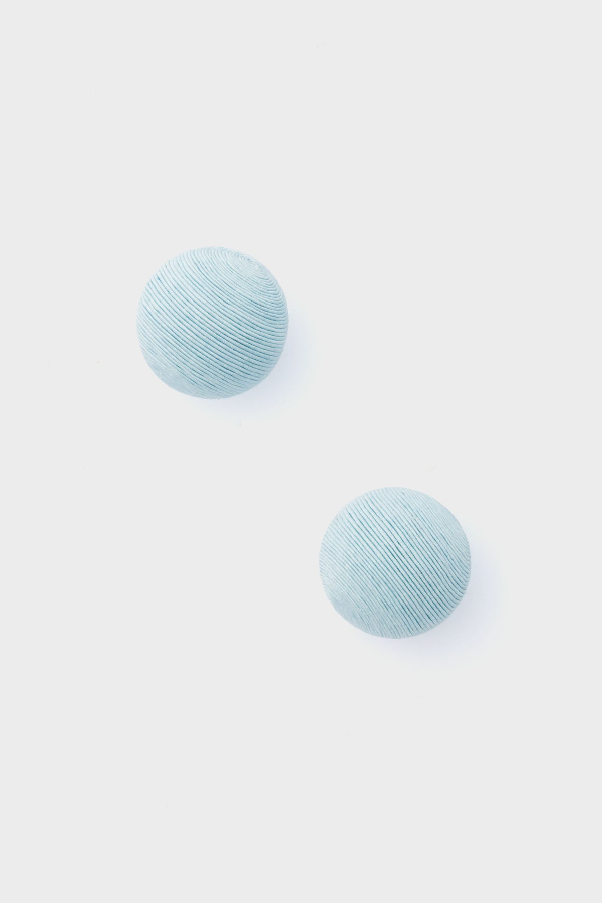 Two round, light blue, textured pieces from Tuckernuck Jewelry—reminiscent of Casey Studs or blue silk earrings—are artfully displayed.