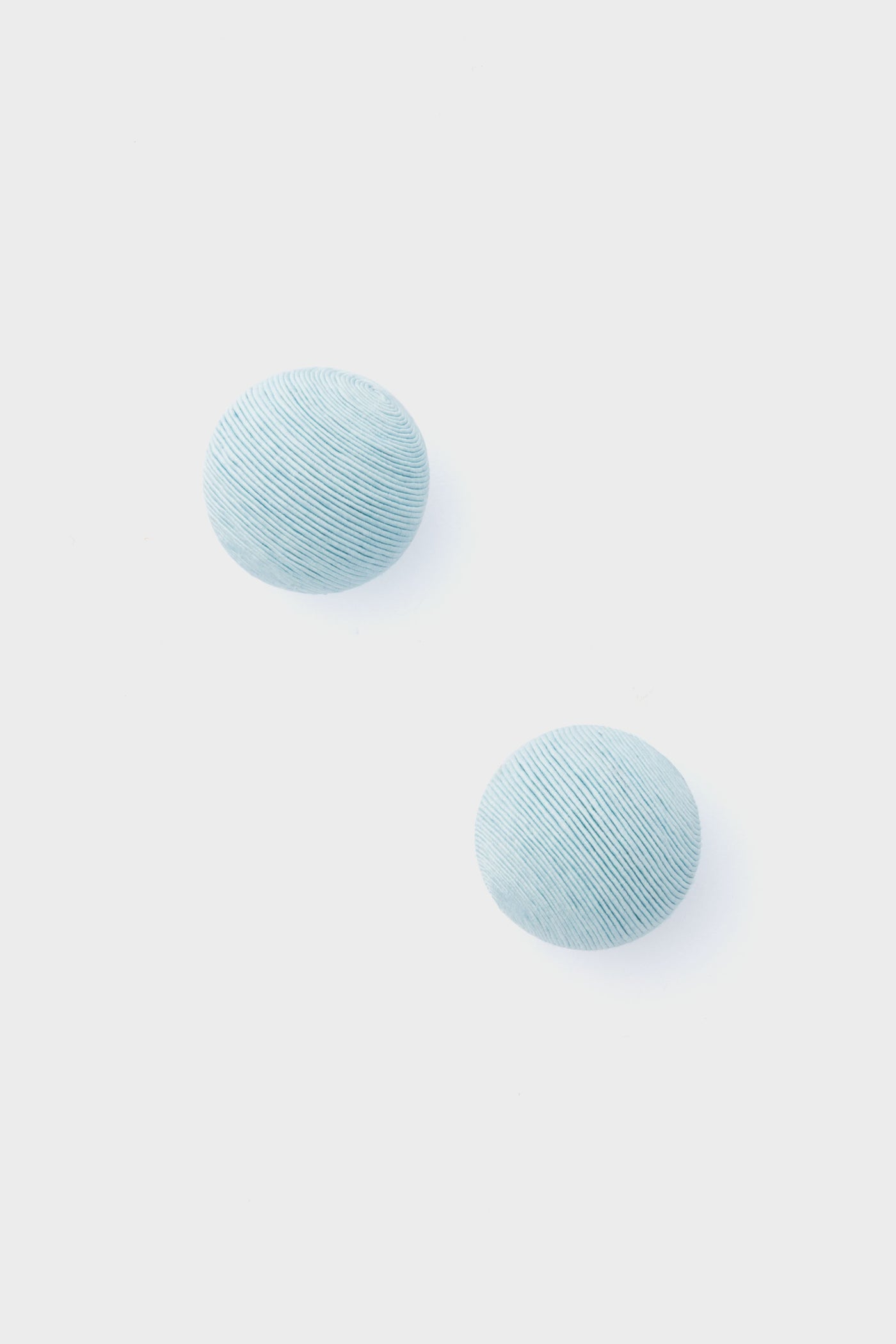 Two round, light blue, textured pieces from Tuckernuck Jewelry—reminiscent of Casey Studs or blue silk earrings—are artfully displayed.