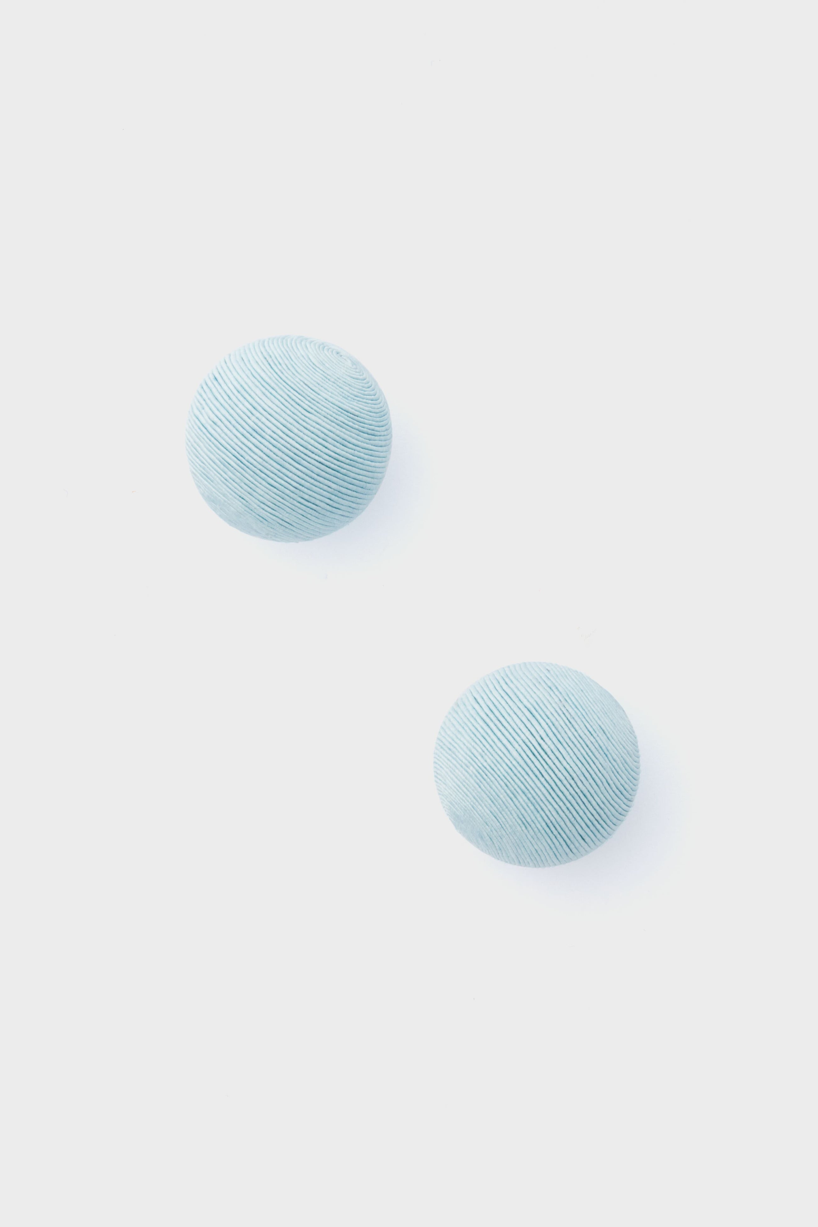 Two round, light blue, textured pieces from Tuckernuck Jewelry—reminiscent of Casey Studs or blue silk earrings—are artfully displayed.