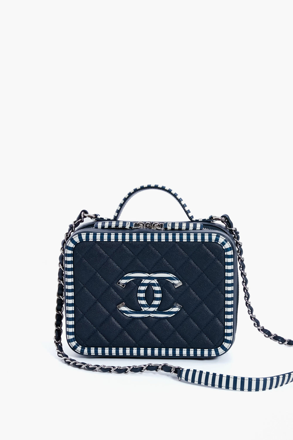 A small rectangular quilted navy vanity bag from the Tuckernuck Archive Collection, featuring a top handle, chain strap, striped edges, and a silver logo on the front.