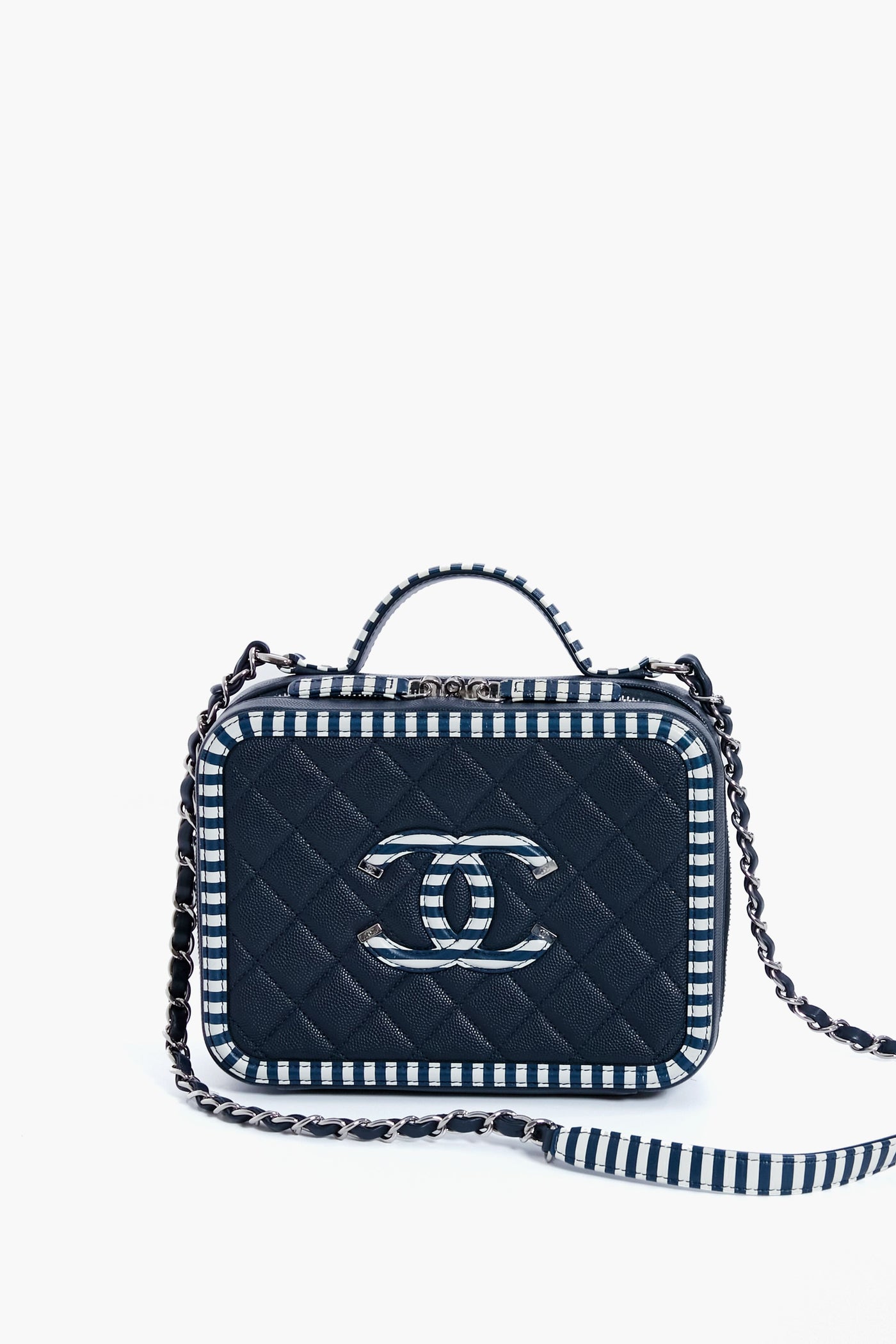 A small rectangular quilted navy vanity bag from the Tuckernuck Archive Collection, featuring a top handle, chain strap, striped edges, and a silver logo on the front.