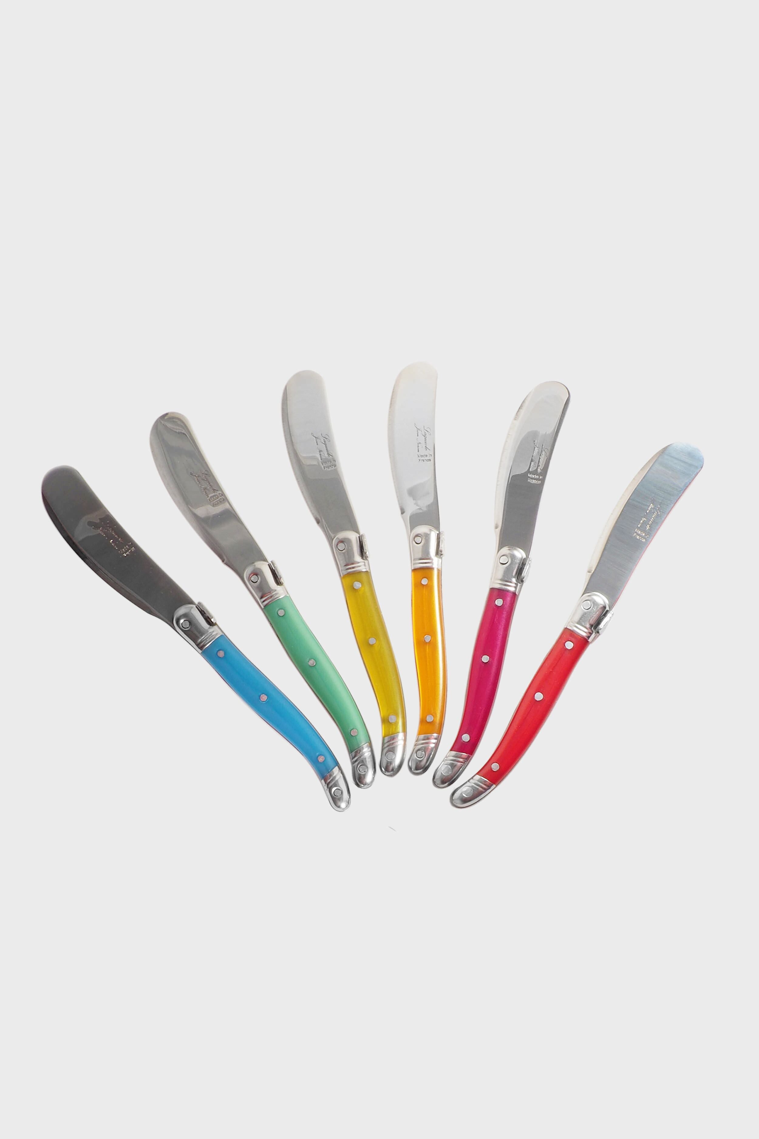 Six Laguiole butter knives with stainless steel blades and colorful handles—black, blue, green, yellow, orange, and red—are arranged in a fan shape. Ideal for any table setting.