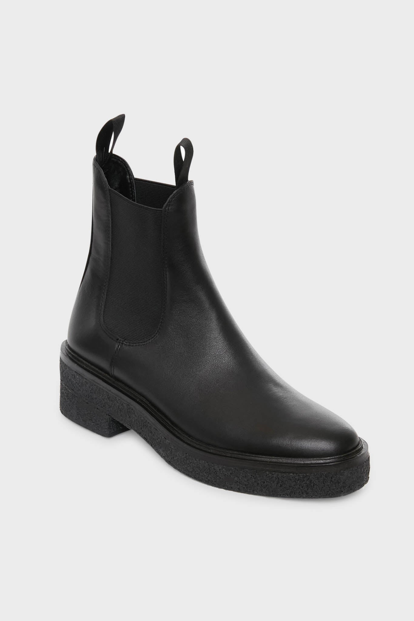 Loeffler Randall’s Black Raquel Boots are black leather Chelsea boots with elastic side panels, front and back pull tabs, and a thick textured sole—offering a modern update on classic platform-heel styles.
