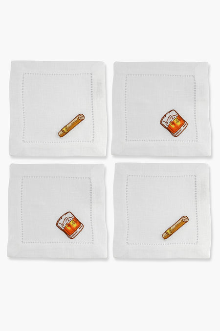 Four white linen cocktail napkins by Chefanie, each hand-embroidered with whiskey, cigar, or beer motifs, arranged neatly in a grid.