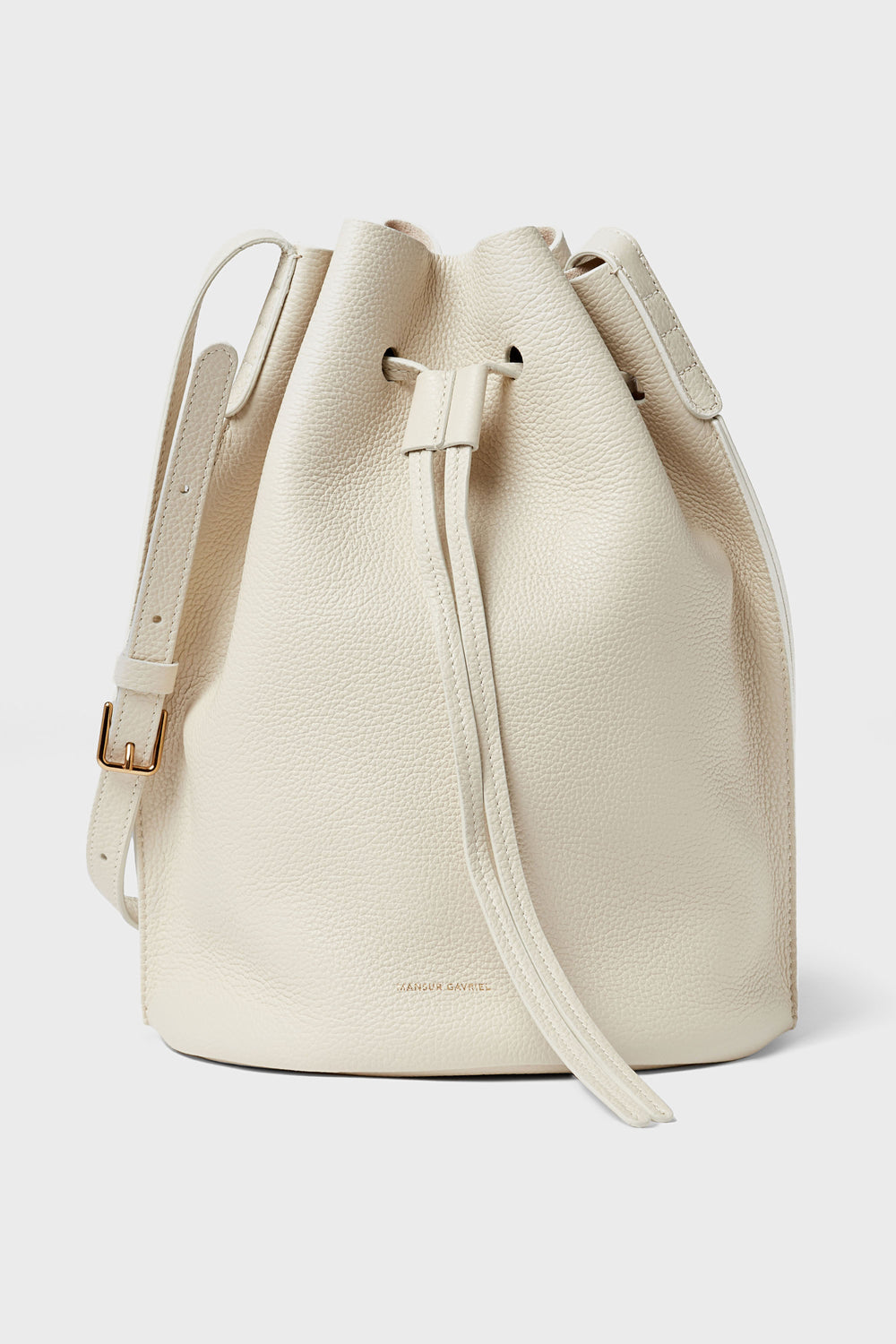 A cream-colored Mansur Gavriel bucket bag made from Italian leather features a drawstring closure and an adjustable shoulder strap.