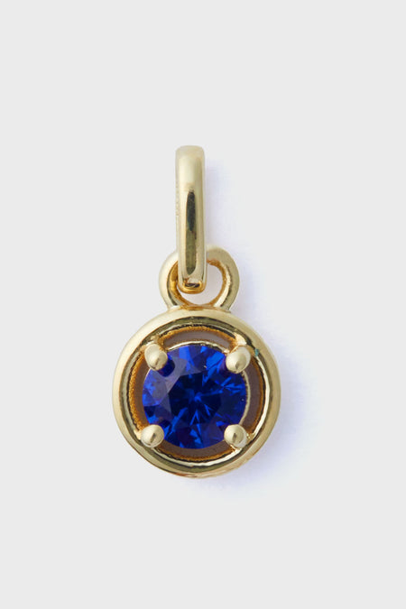 Tuckernuck Fine Jewelry 14k gold pendant with a round sapphire charm in a four-prong setting and a simple gold loop for easy attachment to any necklace.