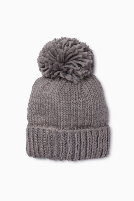 The Look by M gray pom beanie features a wide folded brim and a large pom-pom on top. This hand knit beanie adds cozy style to any outfit.