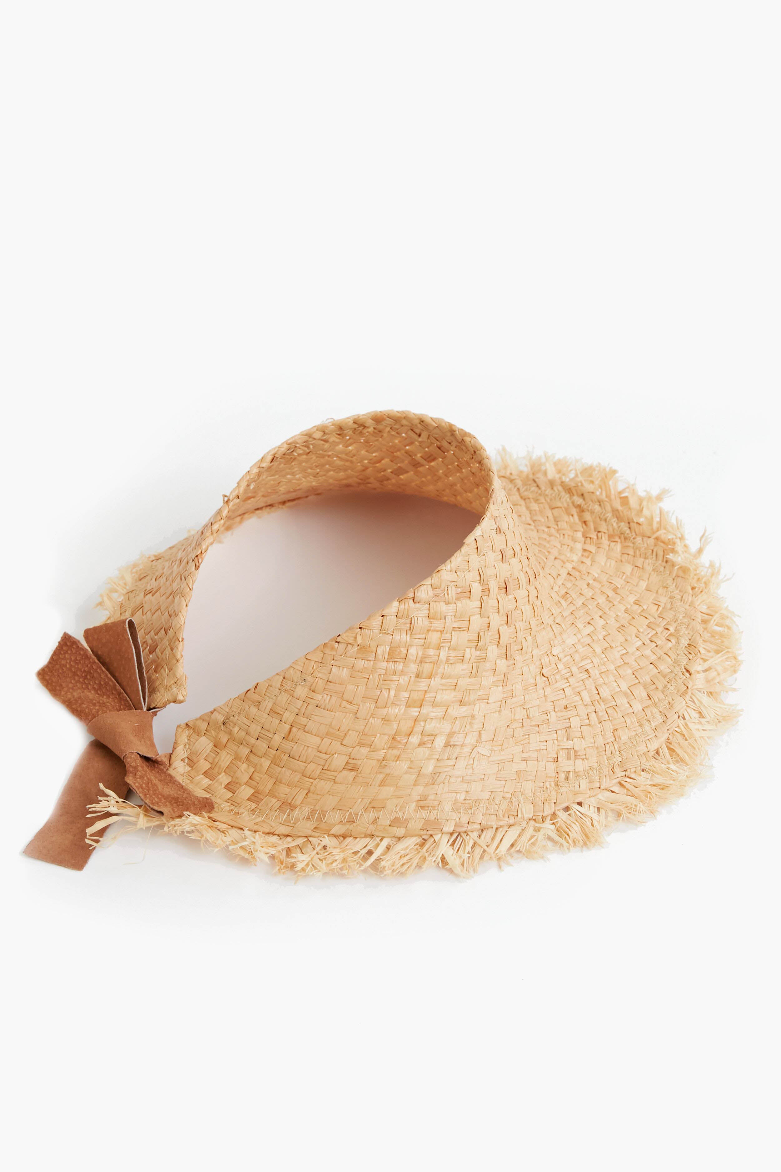 A woven raffia visor hat with a frayed brim and a brown suede bow accent on the side by Wyeth.