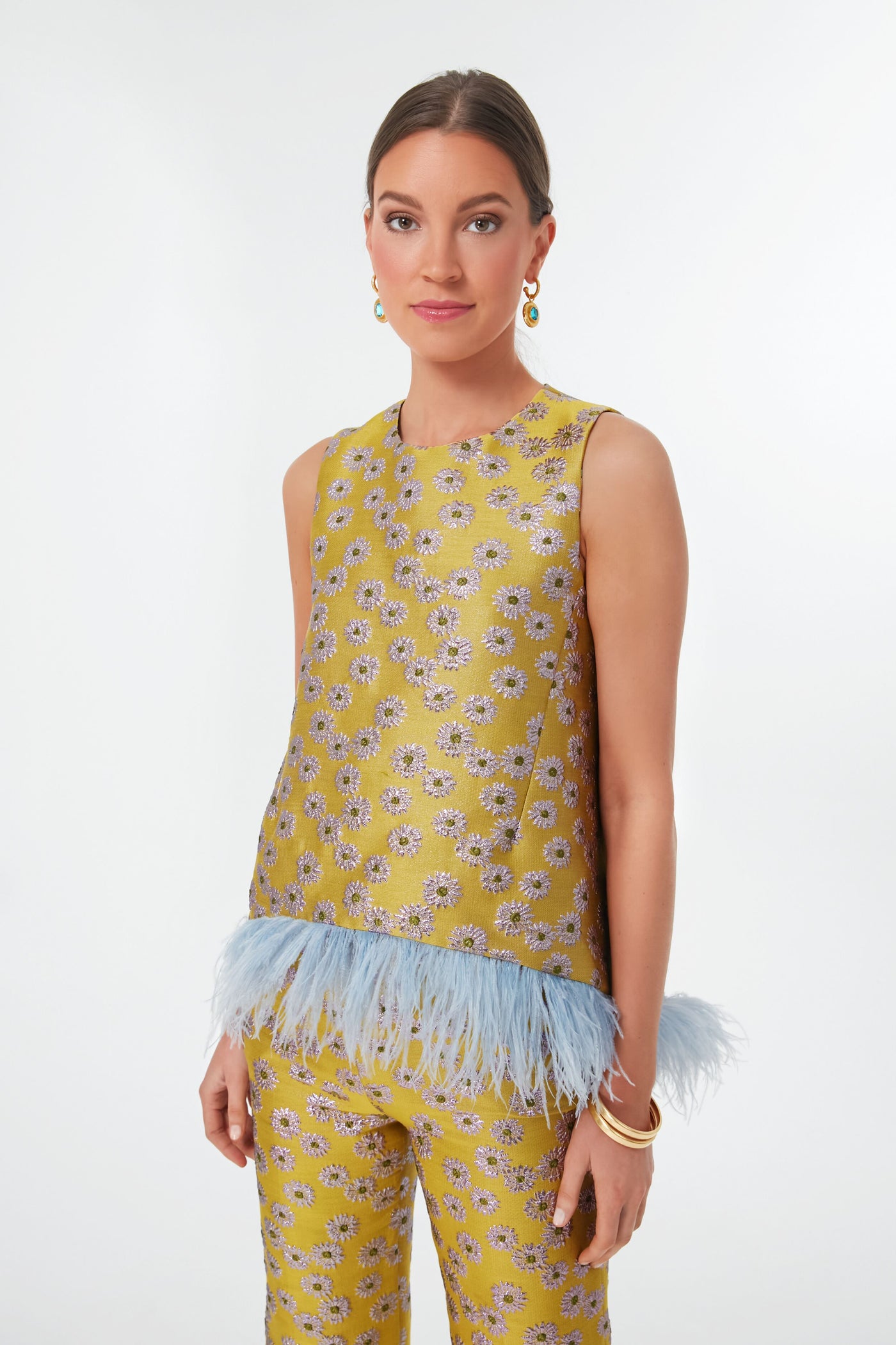 Woman wears a yellow floral sleeveless La DoubleJ Margarita La Scala Top in embroidered jacquard with blue ostrich feather trim, paired with matching pants.