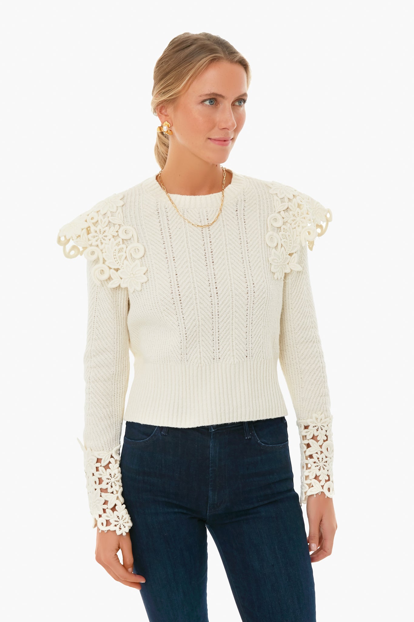 A woman wears a Sea New York textured knit white sweater with lace details on the shoulders and cuffs, paired with dark blue jeans.