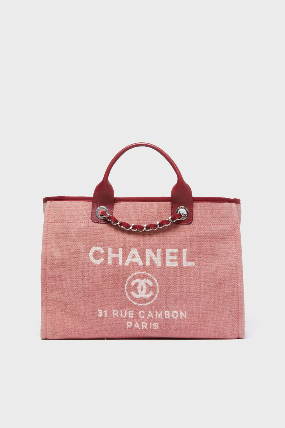 A pink Tuckernuck Archive Collection Deauville Tote featuring red leather handles, silver chain details, and white "31 RUE CAMBON PARIS" logo text on the front.