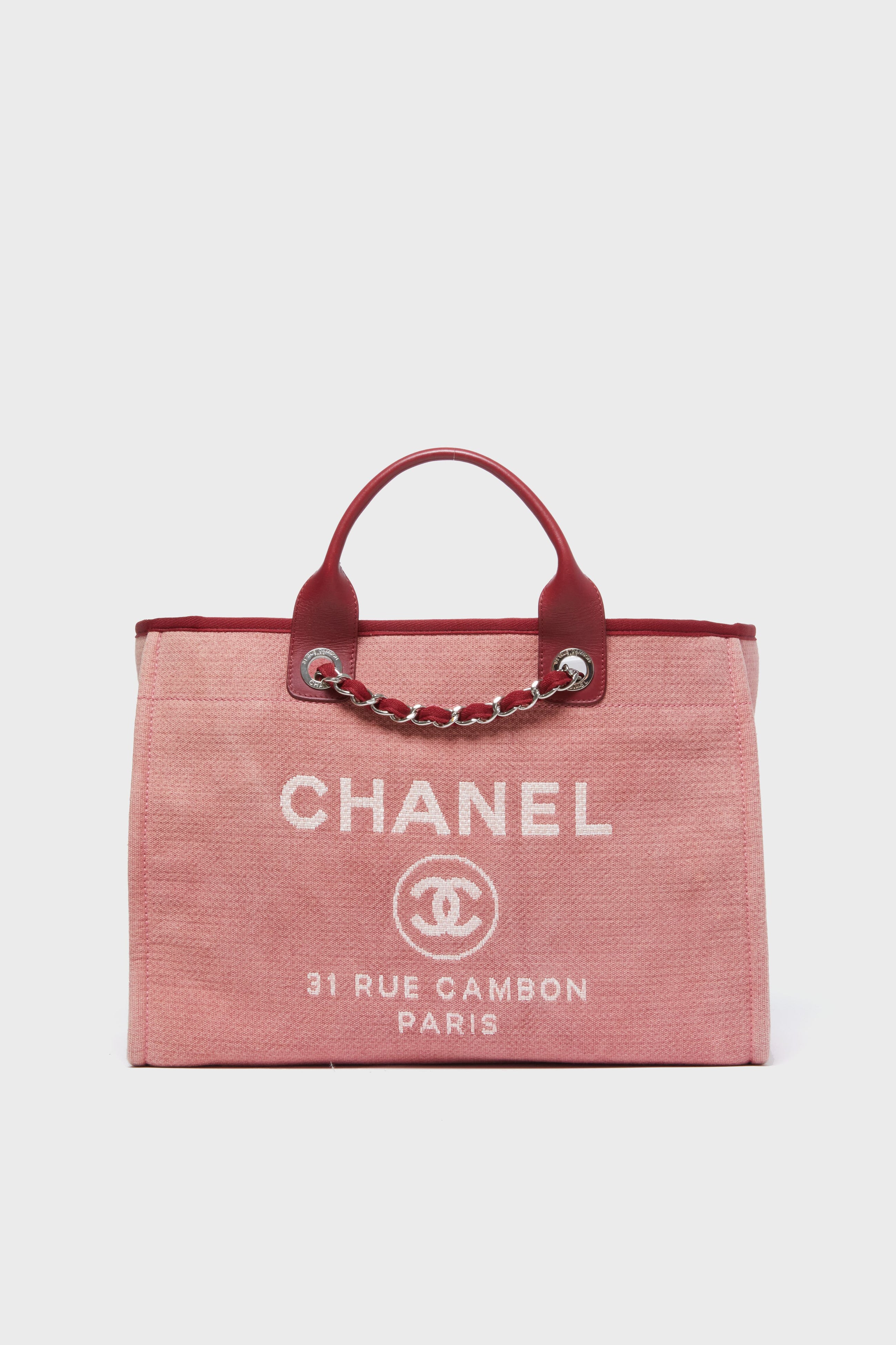 A pink Tuckernuck Archive Collection Deauville Tote featuring red leather handles, silver chain details, and white "31 RUE CAMBON PARIS" logo text on the front.
