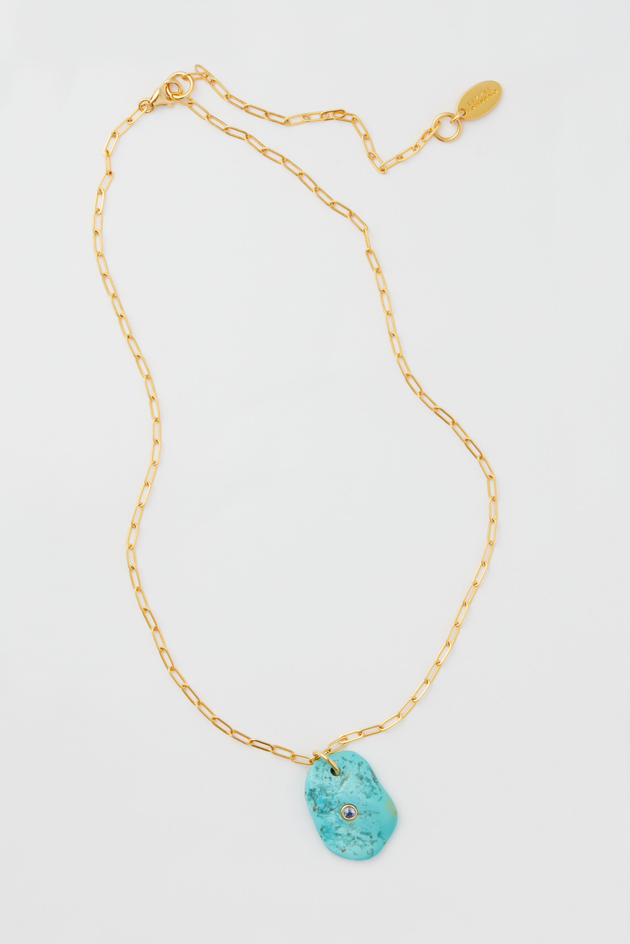 Lizzie Fortunato gold paperclip chain necklace featuring an irregular turquoise pendant with a small embedded crystal—a striking statement piece.