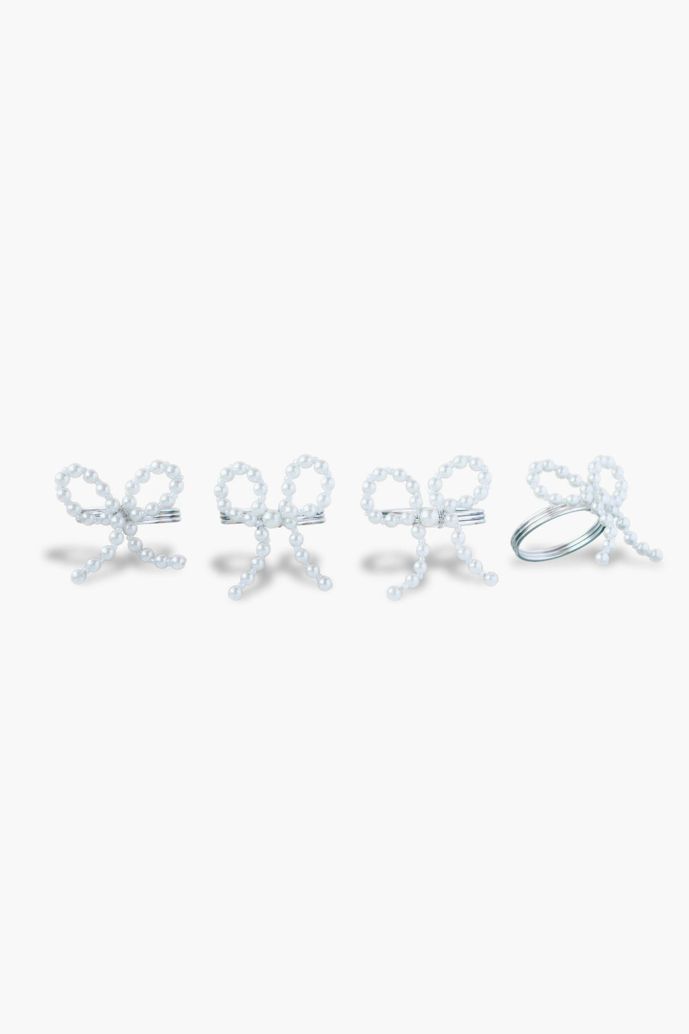 The Chefanie Pearl Bow Napkin Rings set features four white beaded rings shaped like bows, arranged in a row, perfect for adding elegant charm to your table decor.