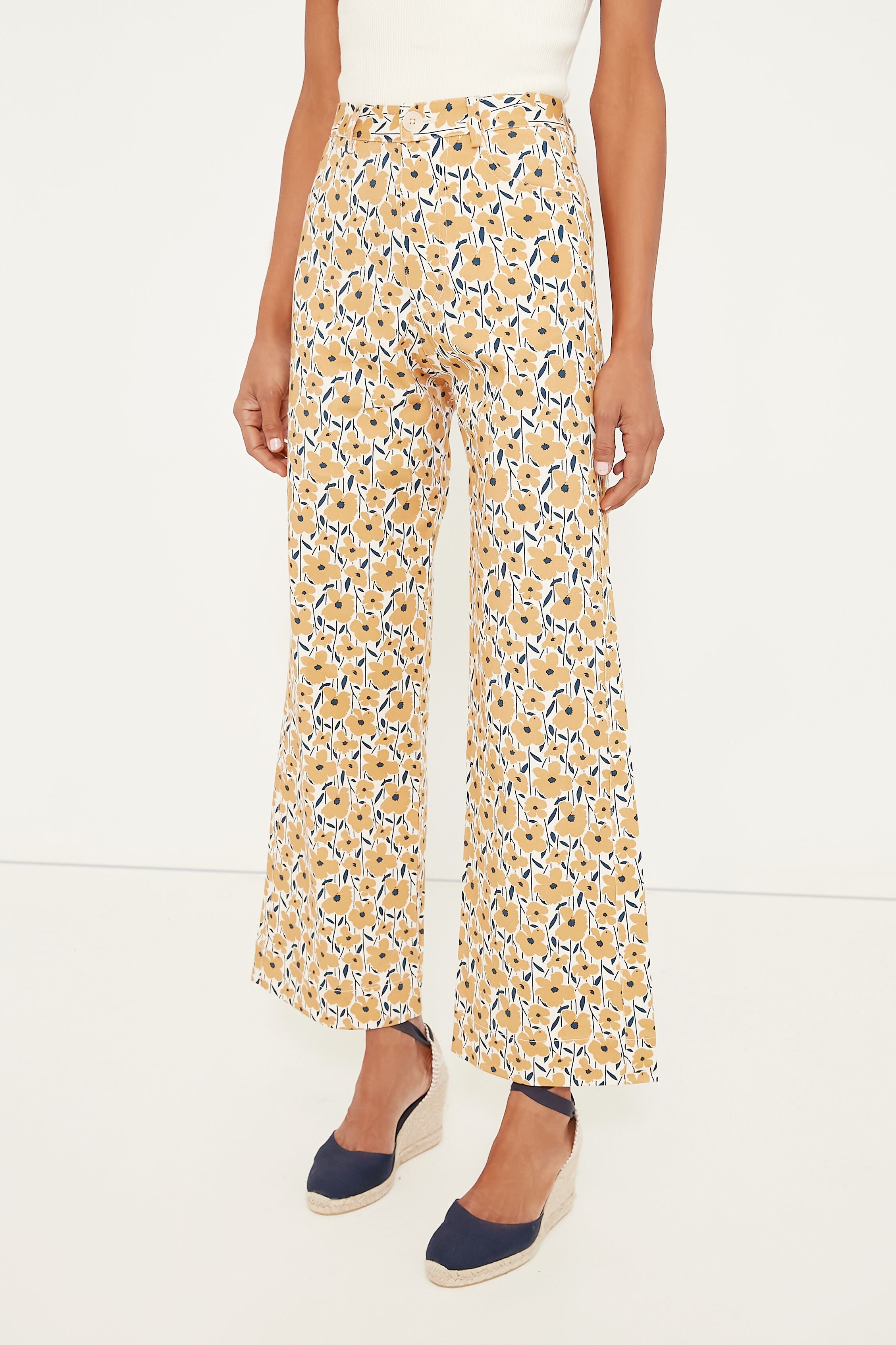 Wearing Emerson Fry high-rise, wide-leg yellow and blue floral print stretch cotton twill pants, a sleeveless white top, and navy espadrille wedge shoes.
