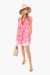Woman wearing a straw hat, boho-chic Poupette St Barth mini dress with red trim, flat sandals, and holding a woven bag.
