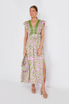 A woman wears the Sheridan French Stacey Dress, a pink and green tiger print silk crepe maxi with ruffled sleeves and a slit, paired with a silver clutch and nude platform sandals.