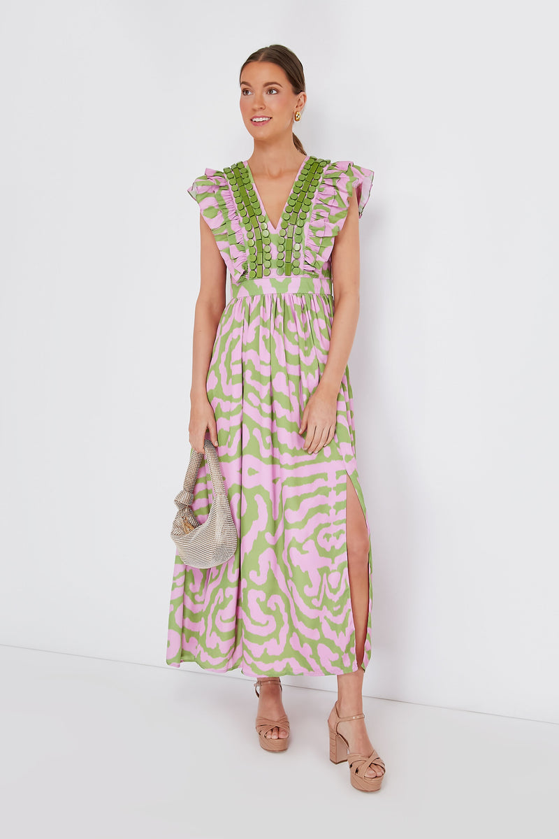 A woman wears the Sheridan French Stacey Dress, a pink and green tiger print silk crepe maxi with ruffled sleeves and a slit, paired with a silver clutch and nude platform sandals.