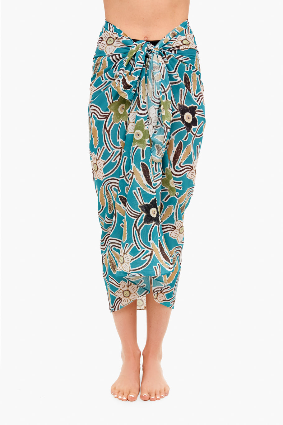 Barefoot individual wears a Ulla Johnson patterned cotton viscose sarong coverup in teal, green, and beige, tied at the waist. Photo captures from shoulders to feet.