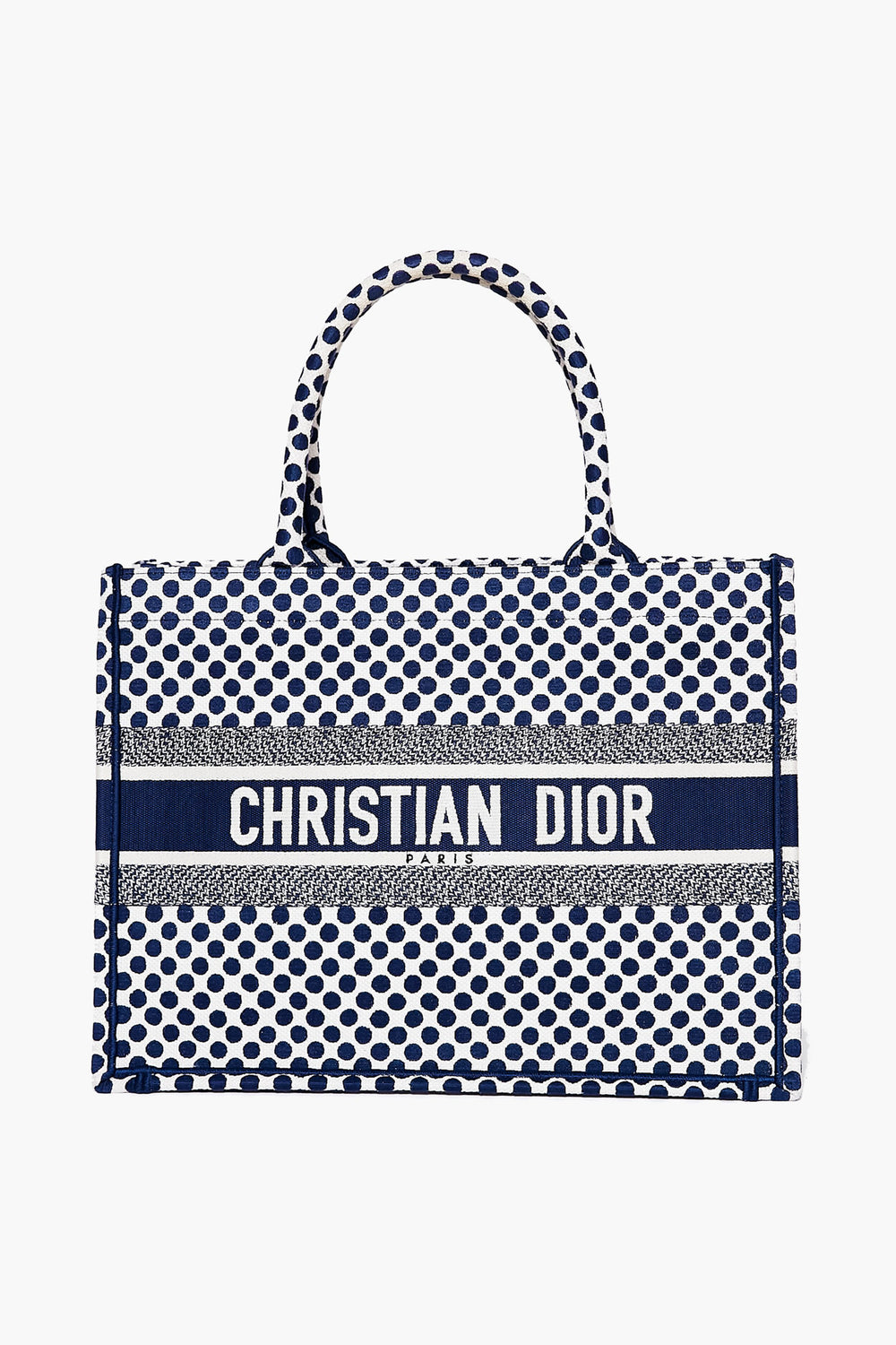A rectangular Tuckernuck Archive Collection Book Tote handbag with a blue and white polka dot pattern, two handles, and the brand name displayed across the front.