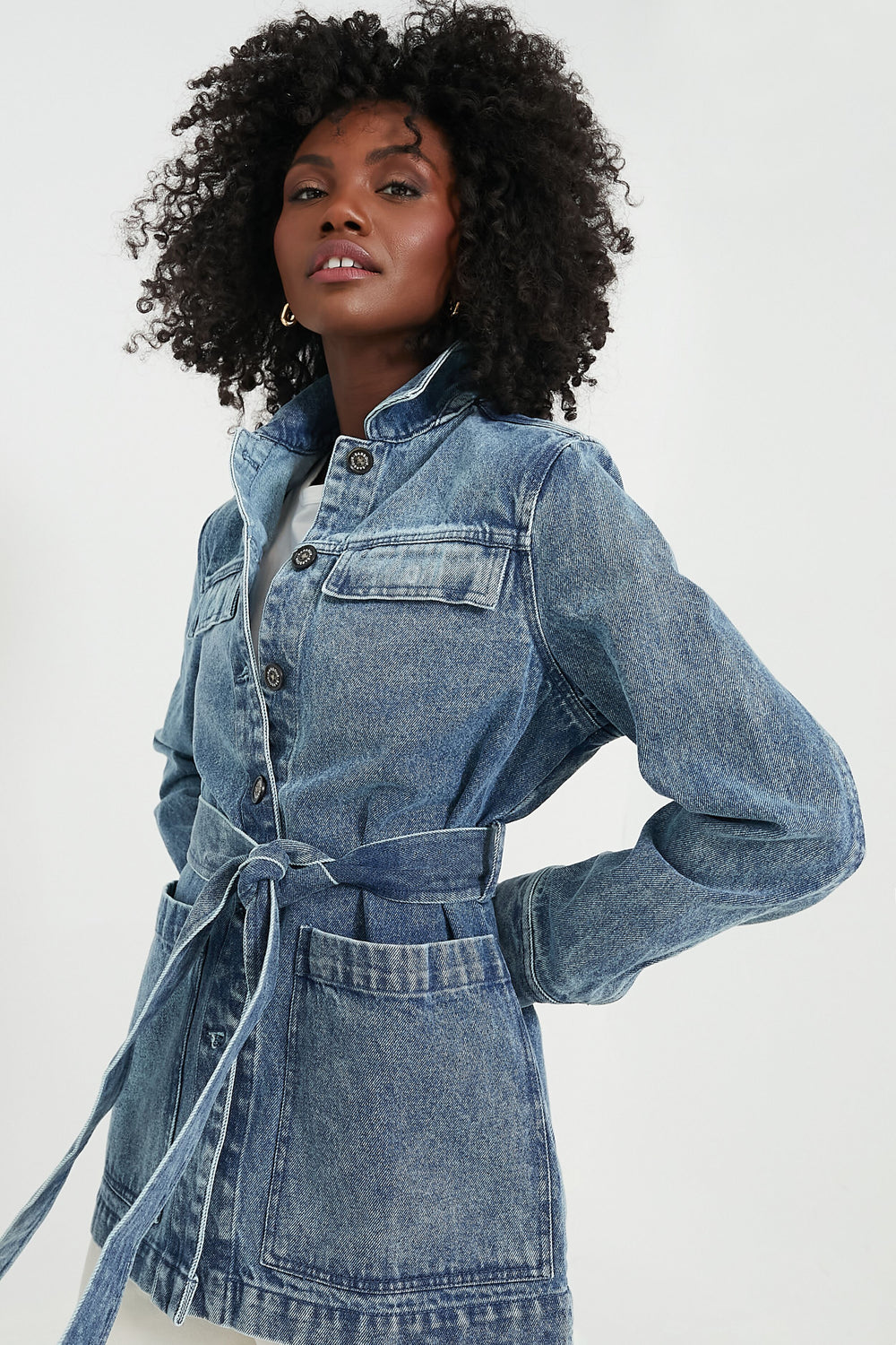 A woman in a Barbour belted denim jacket with chest pockets and button closures, styled like an Indigo Chambray Barbour overshirt—an iconic women’s outerwear piece.