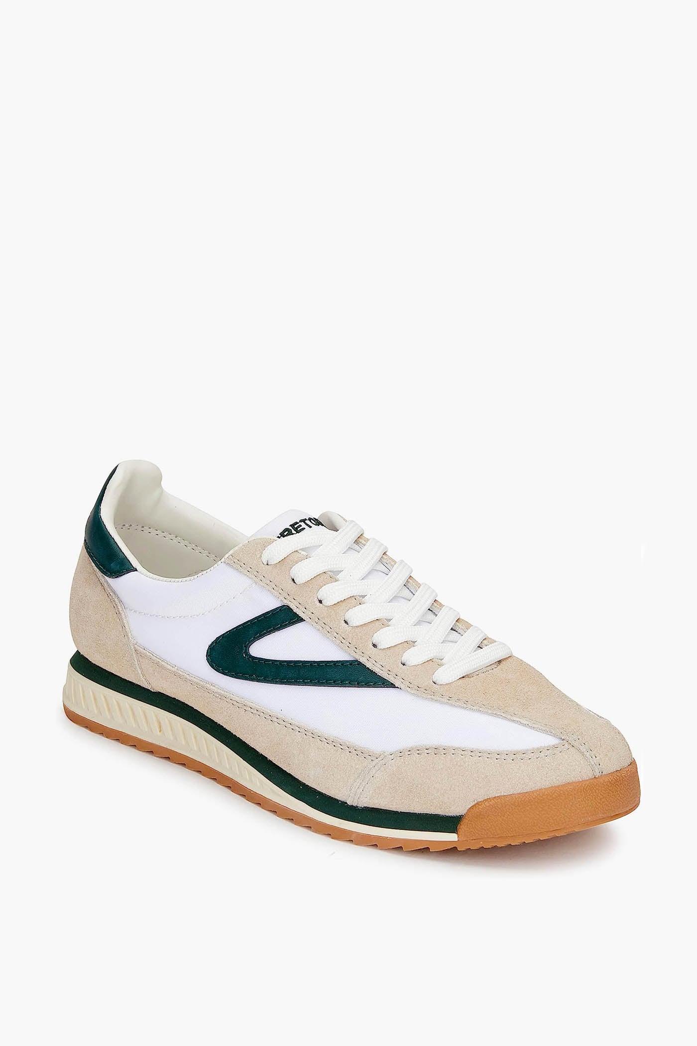 The Tretorn women's sneaker features beige, white, and dark green canvas in a low-top retro design with white laces and a textured gum sole.