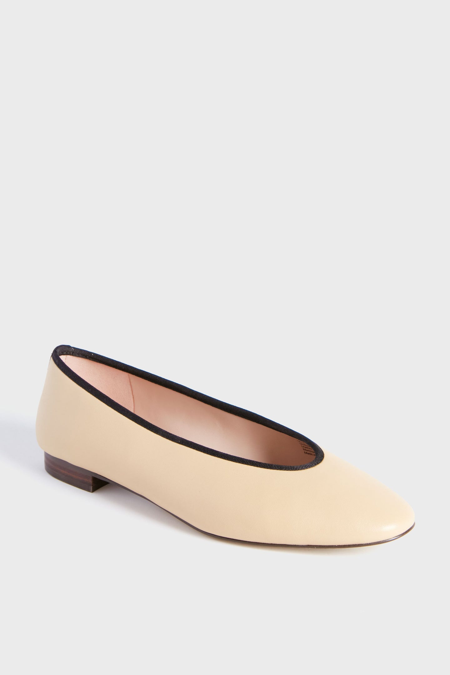 The Tuckernuck Shoes Nude Nina Flats are beige leather ballet flats with black trim and a low wooden heel, combining style and comfort—ideal office shoes for everyday wear.