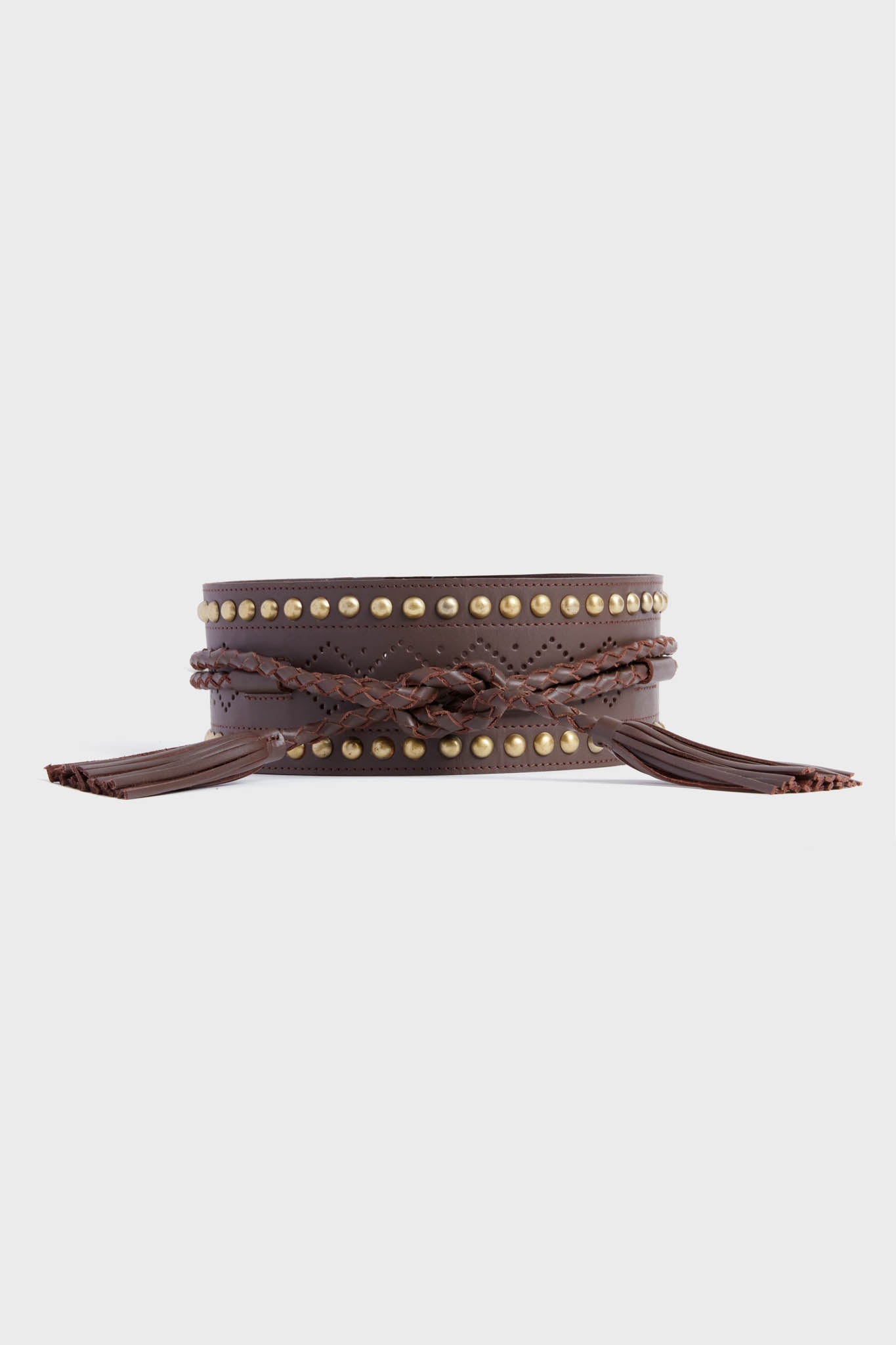 The Figue wide dark brown leather belt features gold studs, braided detailing, and fringed tassels at each end—perfect as a Western-inspired waistbelt.