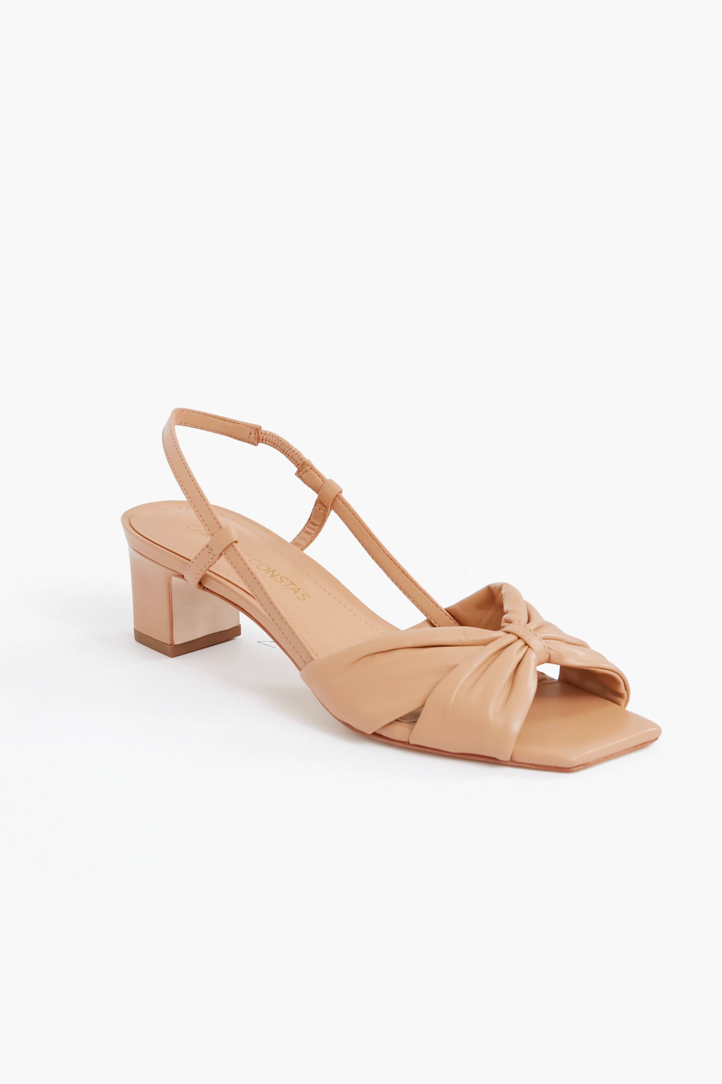 The Caroline Constas tan, open-toe slingback block heel sandal features a low heel, square toe, and knotted front strap.