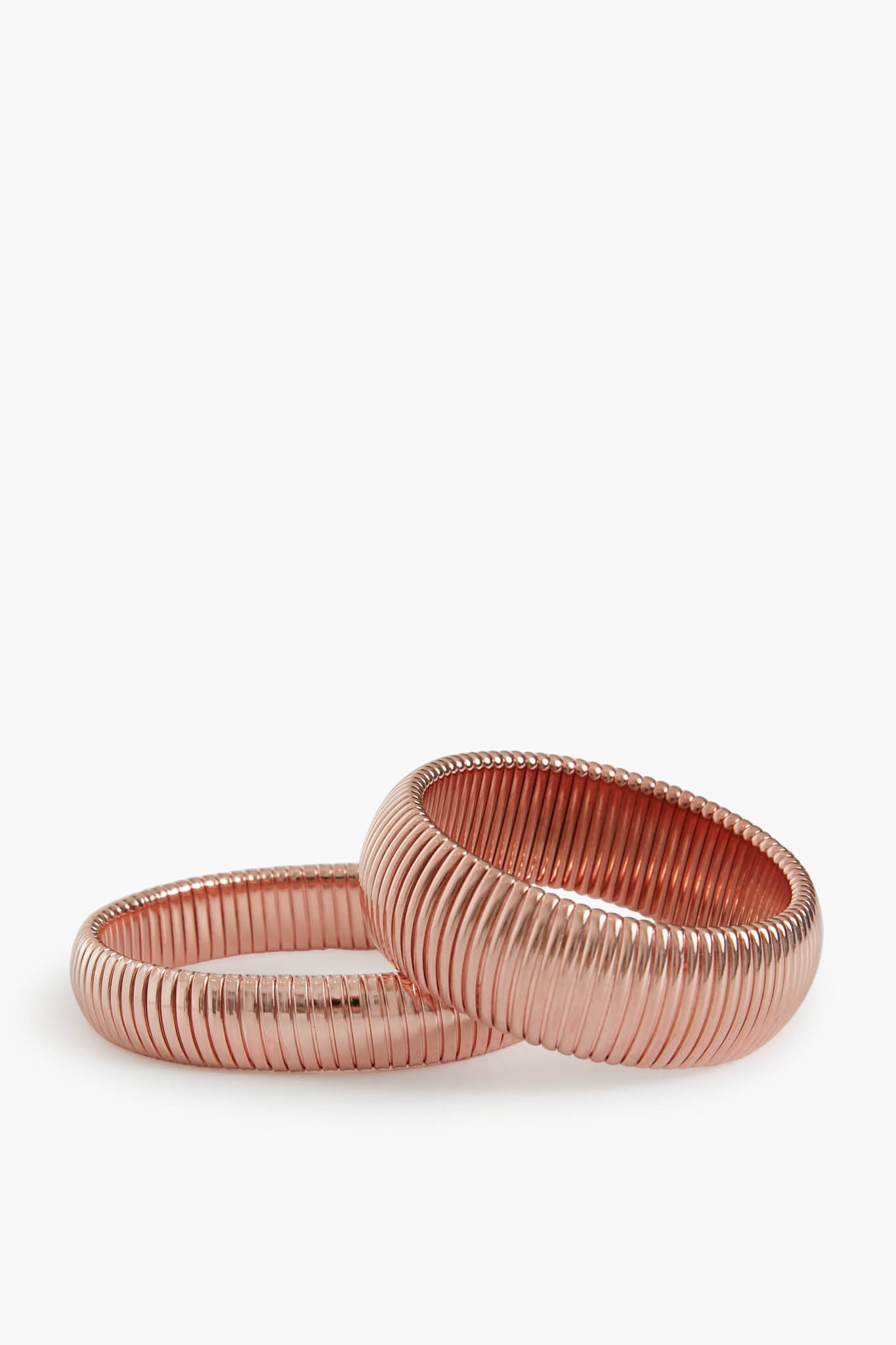 Two rose gold ribbed metal bangles by Ben Amun, crafted from gold-plated brass, are stacked together for a bold statement jewelry piece.