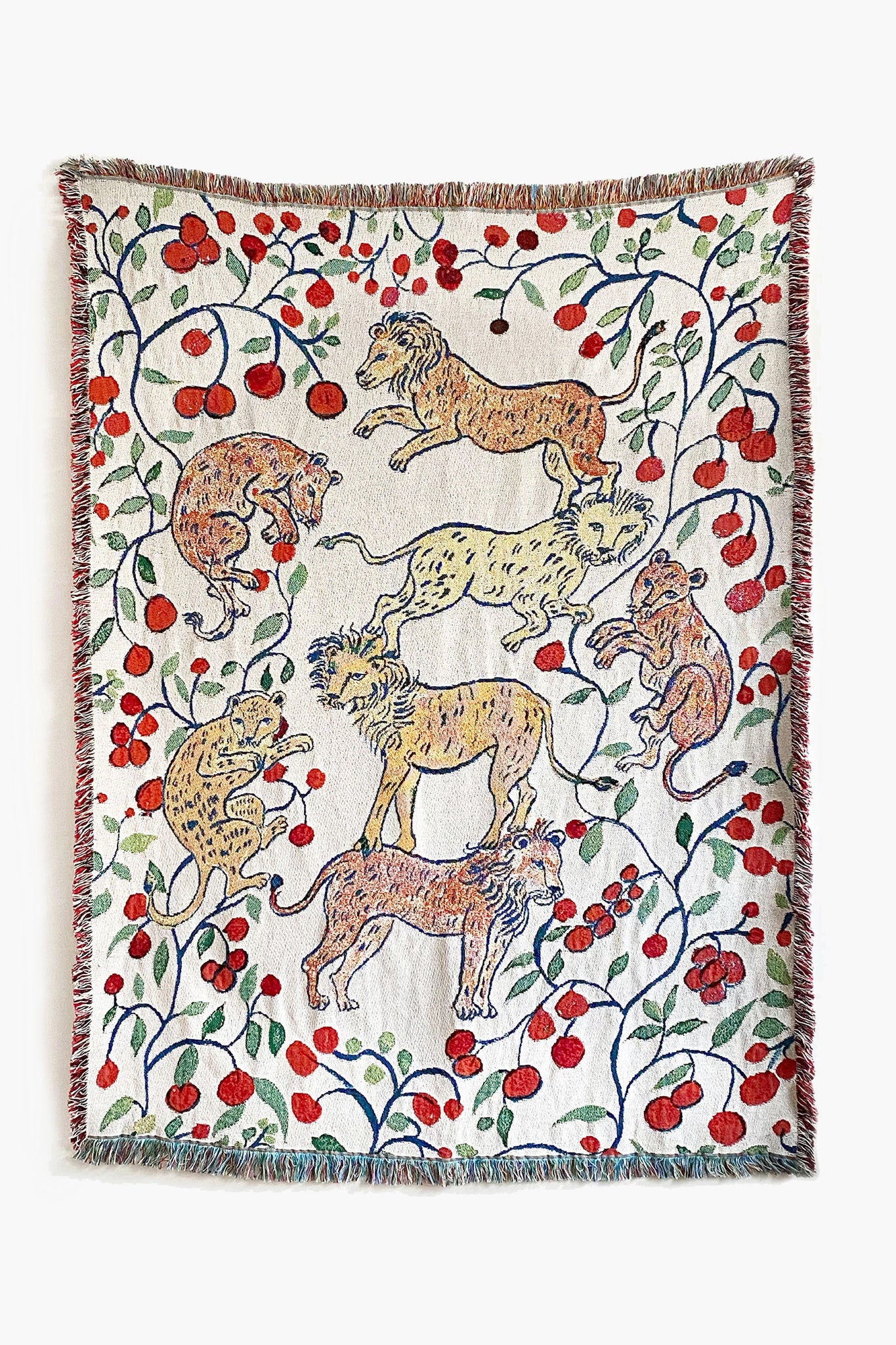 The Olivia Wendel woven throw features six pomegranate lions amid red flowers and green vines, crafted from US-grown cotton and finished with a multicolored fringe.
