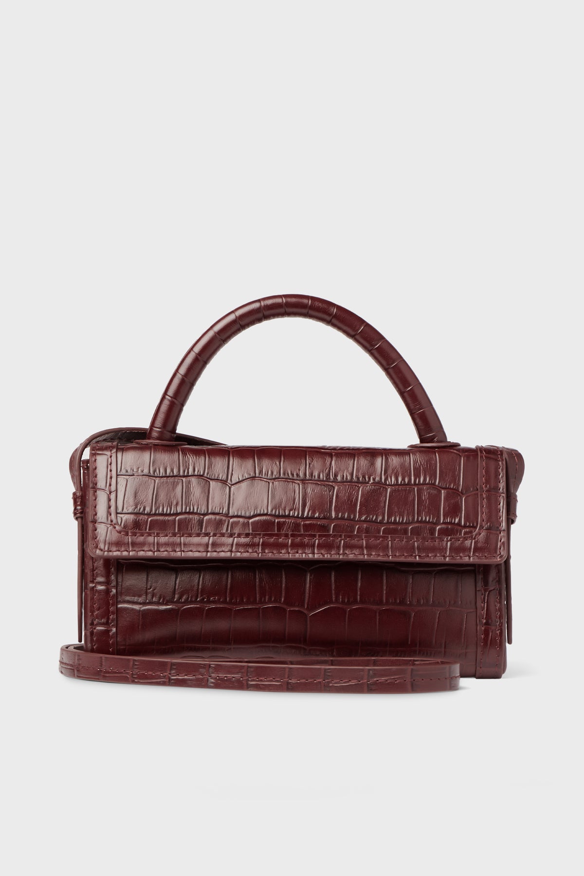 A Neely & Chloe burgundy embossed leather handbag with a crocodile texture, top handle, and long shoulder strap is displayed.