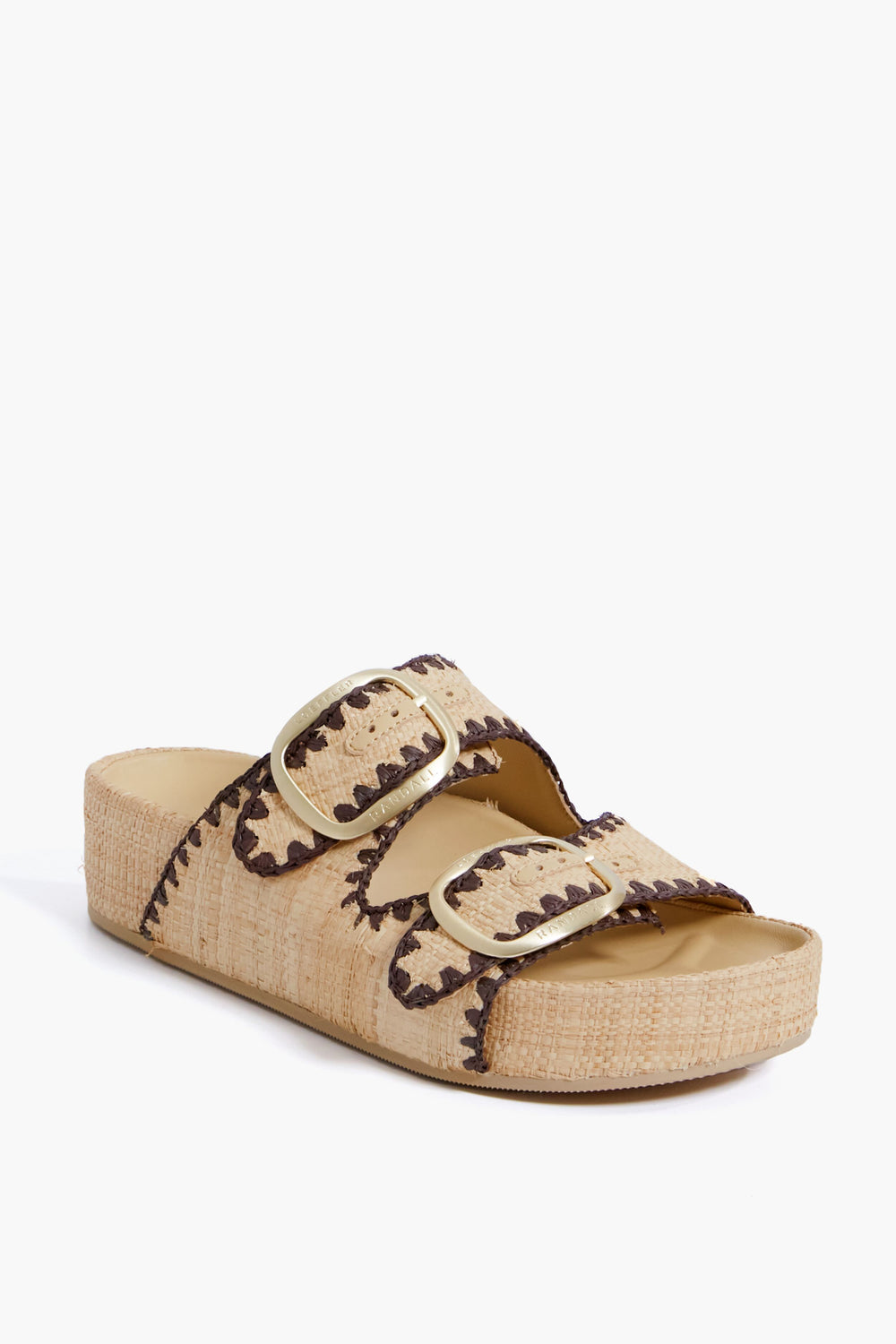 The Loeffler Randall beige straw two-band sandal features gold buckles, brown zigzag stitching, and a flat open-toe platform sole.