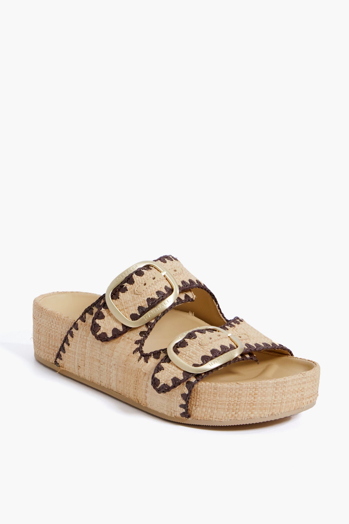 The Loeffler Randall beige straw two-band sandal features gold buckles, brown zigzag stitching, and a flat open-toe platform sole.