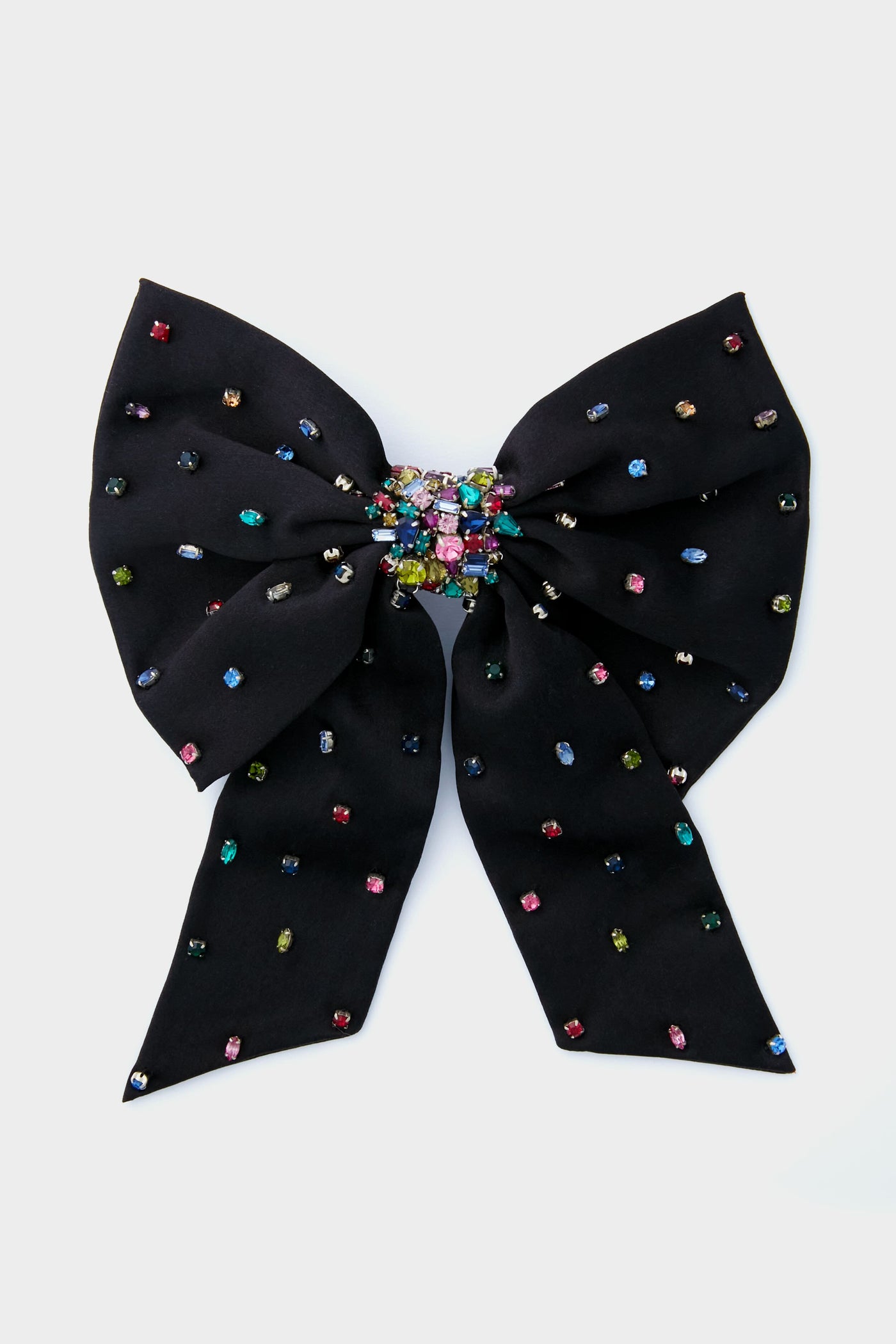 The Mignonne Gavigan Black Grace Bow Hairclip features a large black fabric bow adorned with multicolored gem accents and a central cluster of vibrant gems, adding an elegant touch to any hairstyle.