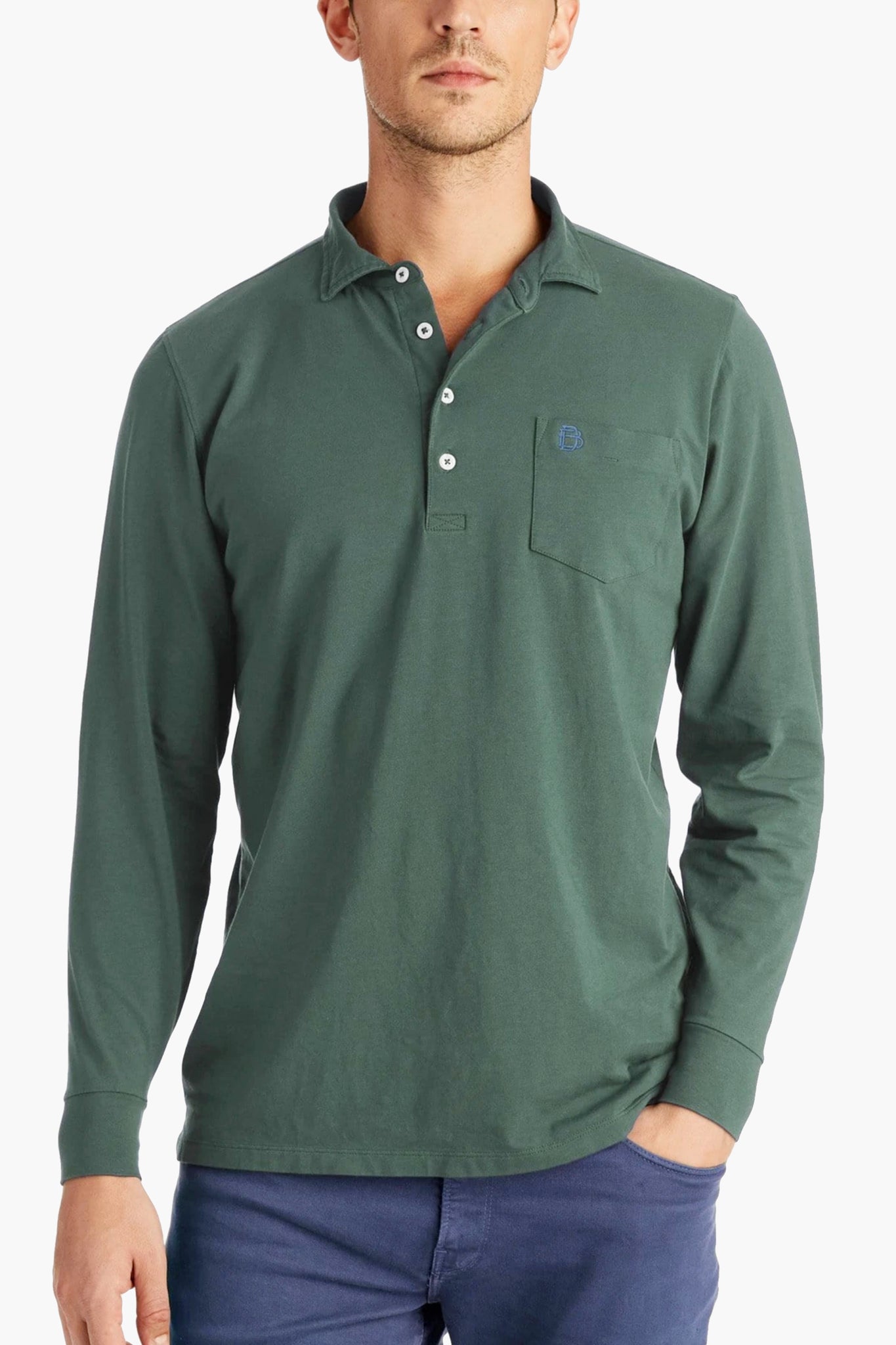 A man wears a B Draddy Peruvian Pima cotton long sleeve polo with a chest pocket and blue buttons, paired with blue pants.