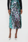 Wearing a Tuckernuck black long-sleeve top, an iridescent sequin party skirt, and pointed silver shoes creates a bold, stylish look.