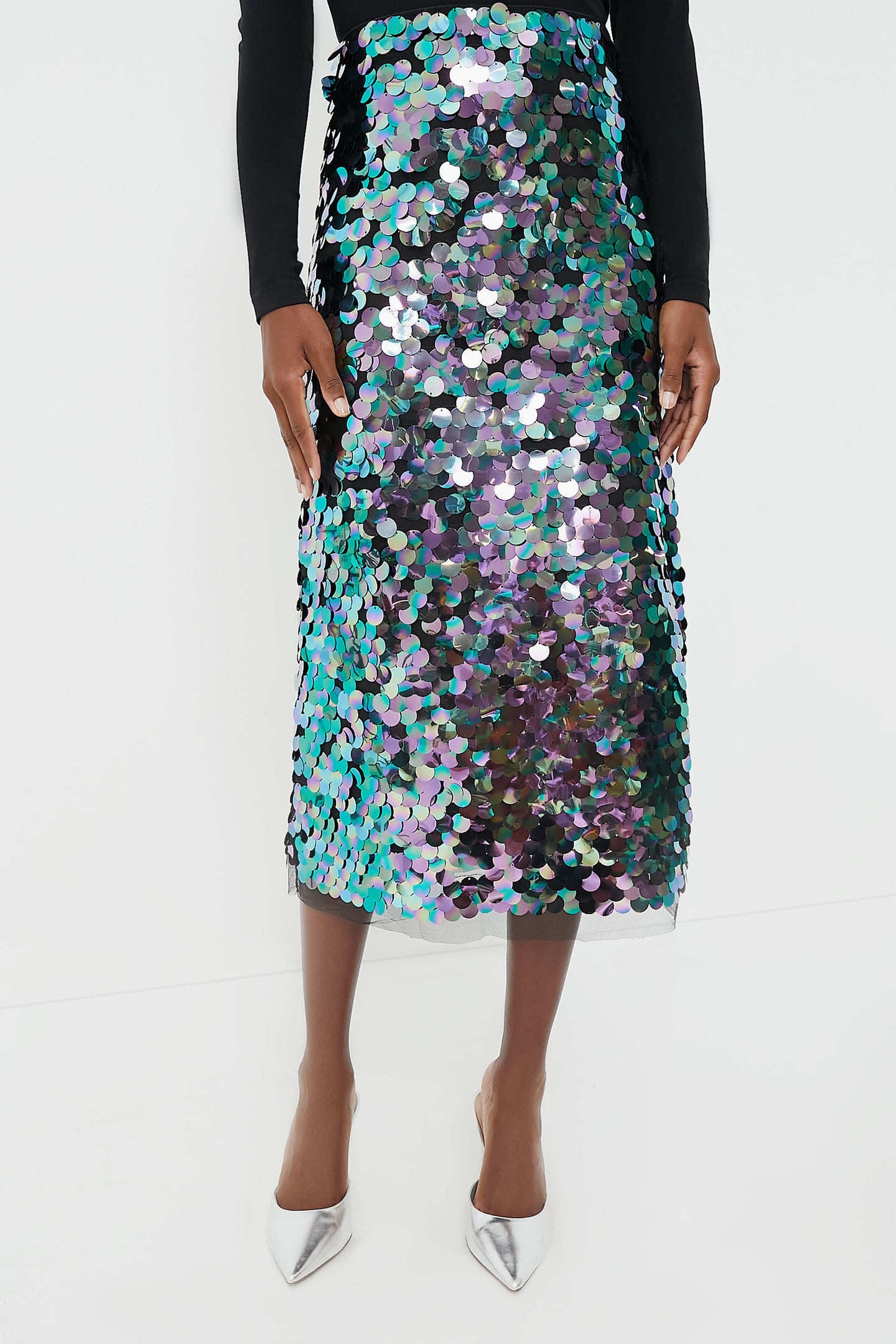 Wearing a Tuckernuck black long-sleeve top, an iridescent sequin party skirt, and pointed silver shoes creates a bold, stylish look.