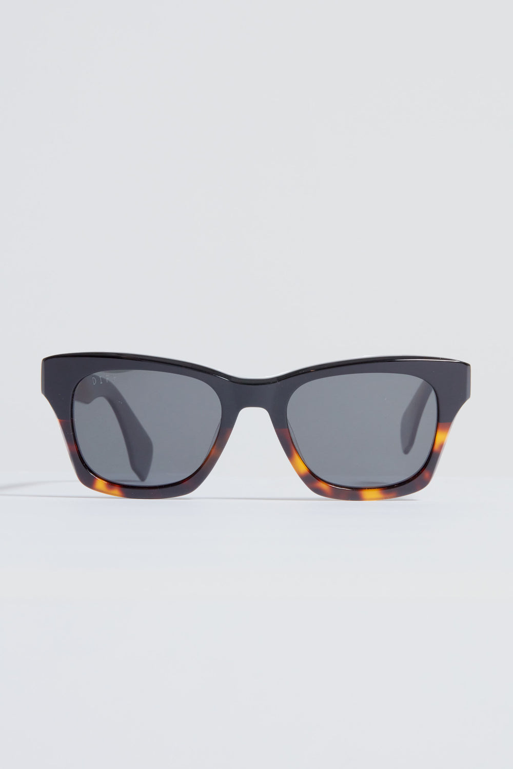 A pair of DIFF Eyewear rectangular tortoiseshell sunglasses with dark lenses rests on a plain white surface.