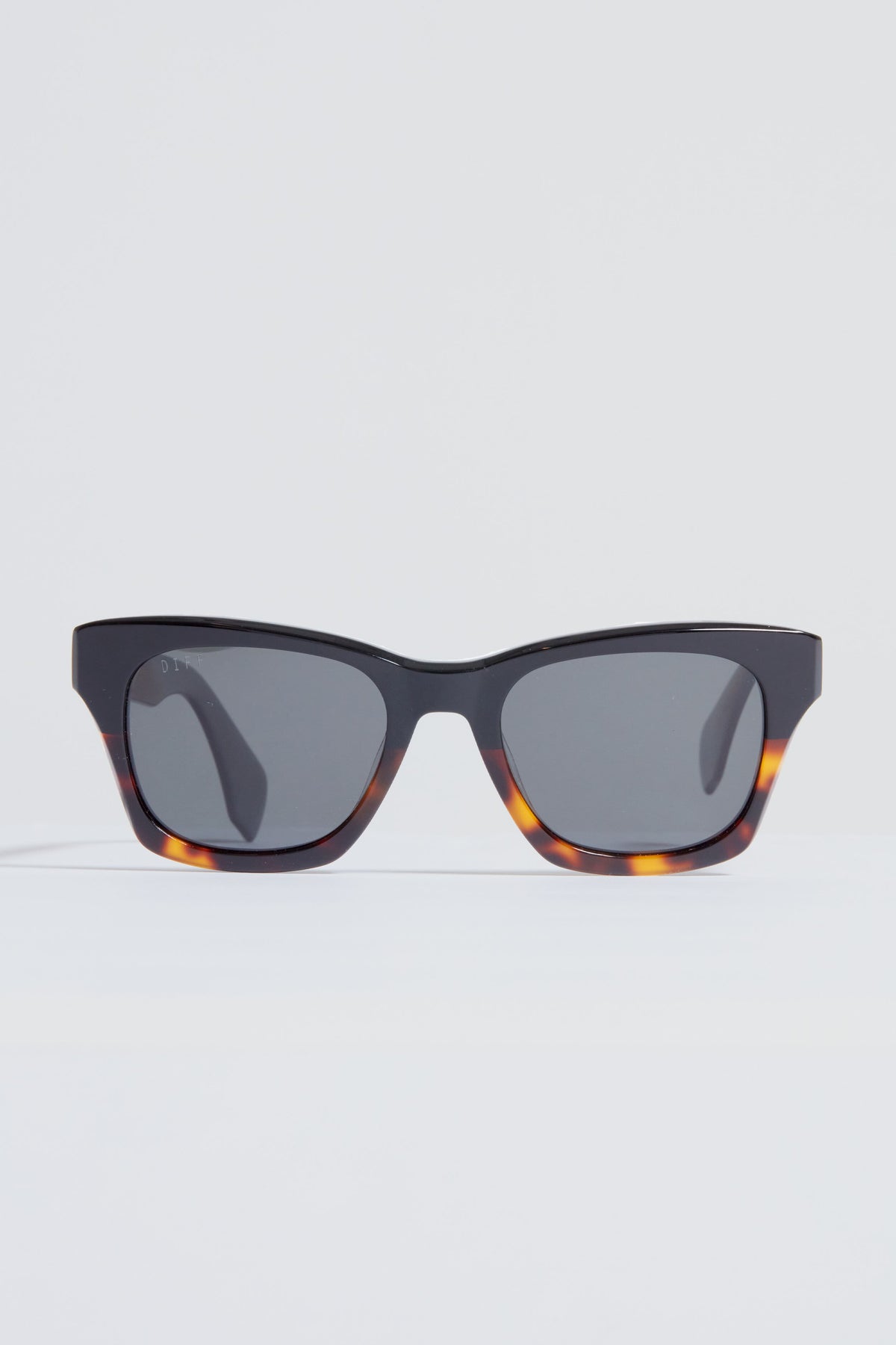 A pair of DIFF Eyewear rectangular tortoiseshell sunglasses with dark lenses rests on a plain white surface.