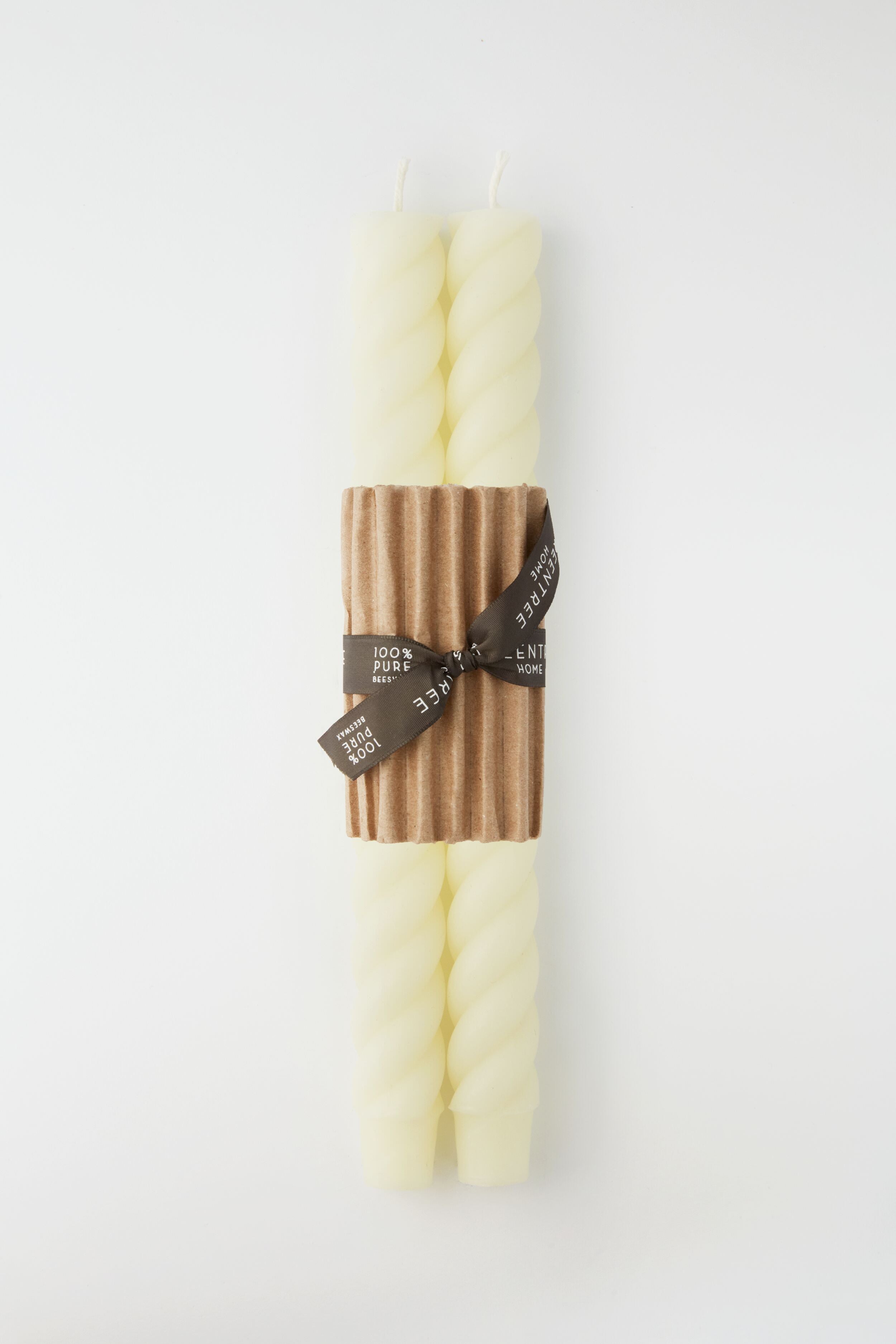 Two ivory spiral taper candles by Greentree Home are bundled with a brown corrugated band and tied with a black ribbon—beautiful hand-poured candles that make a thoughtful housewarming gift.