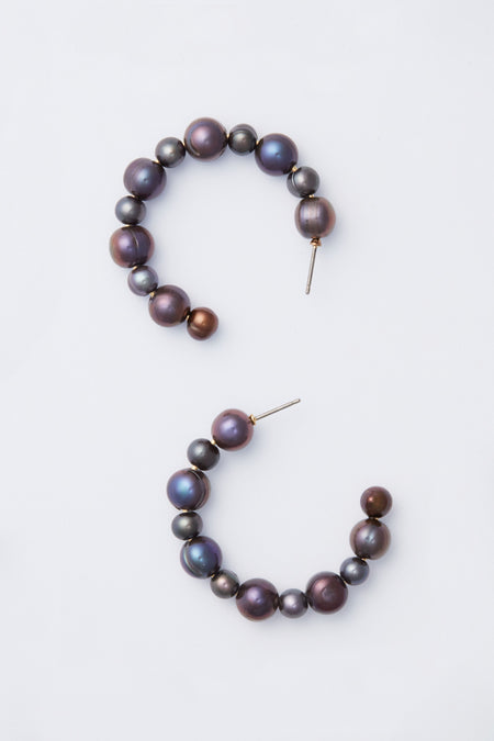 A pair of open gold hoop earrings with round, iridescent dark pearls in a half-circle design—an elegant piece by Tuckernuck Jewelry.
