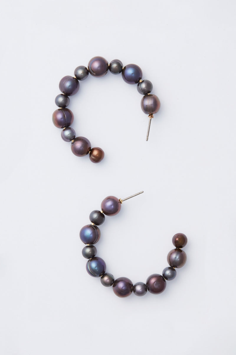 A pair of open gold hoop earrings with round, iridescent dark pearls in a half-circle design—an elegant piece by Tuckernuck Jewelry.