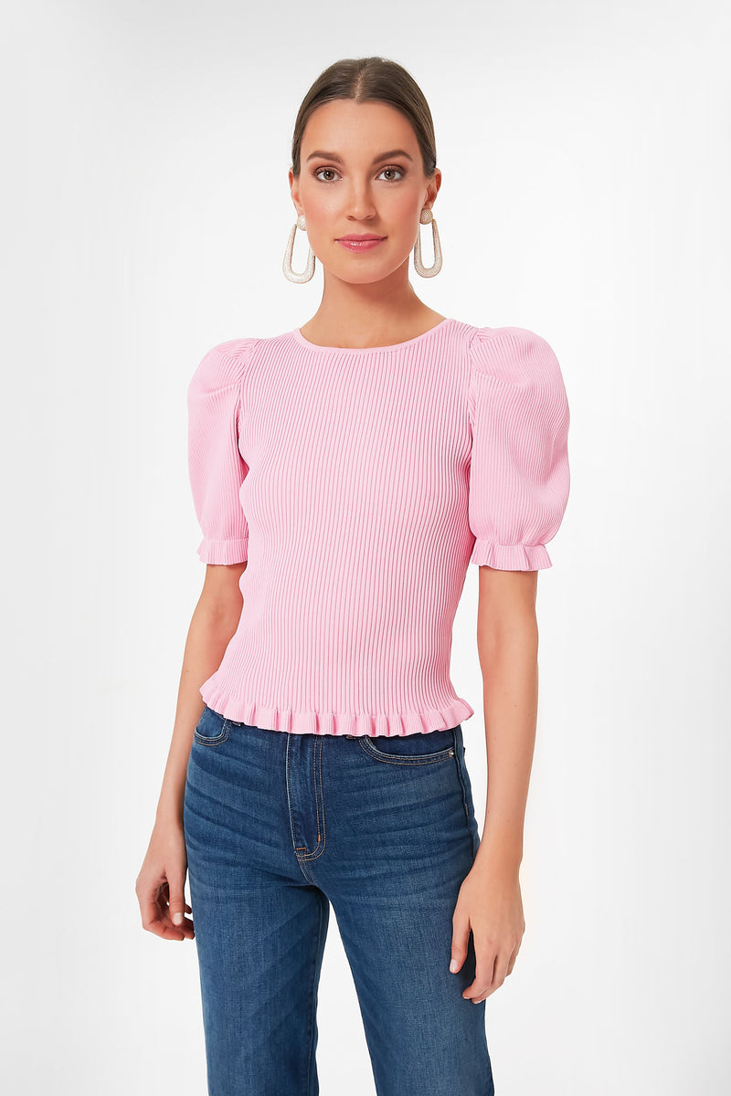 A woman wears a Hyacinth House light pink short-sleeve blouse with ruffle details and puffed sleeves, paired with blue jeans.