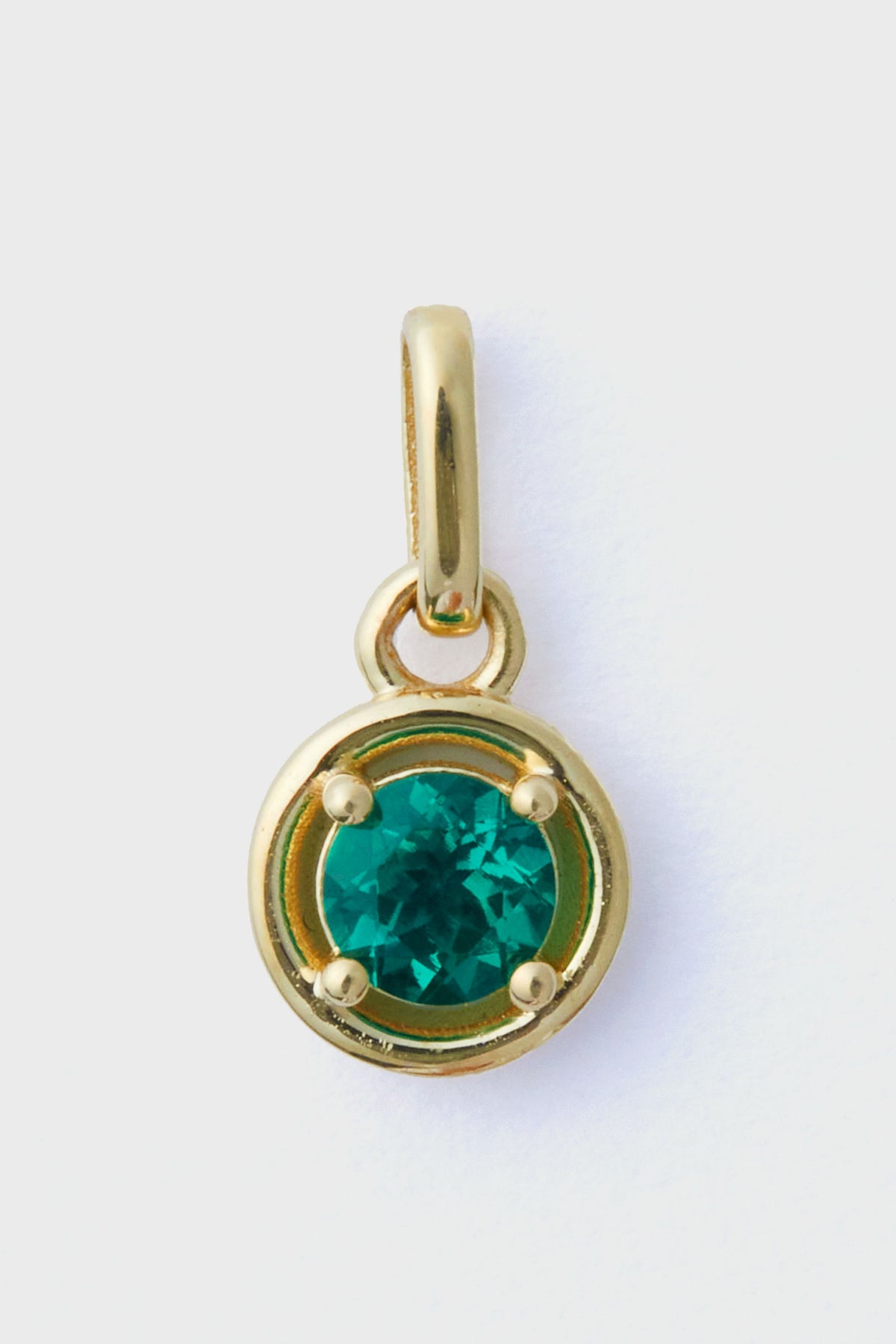 The Tuckernuck Fine Jewelry gold pendant features a round emerald charm at its center, crafted from 14k gold—an exquisite piece of luxury jewelry.