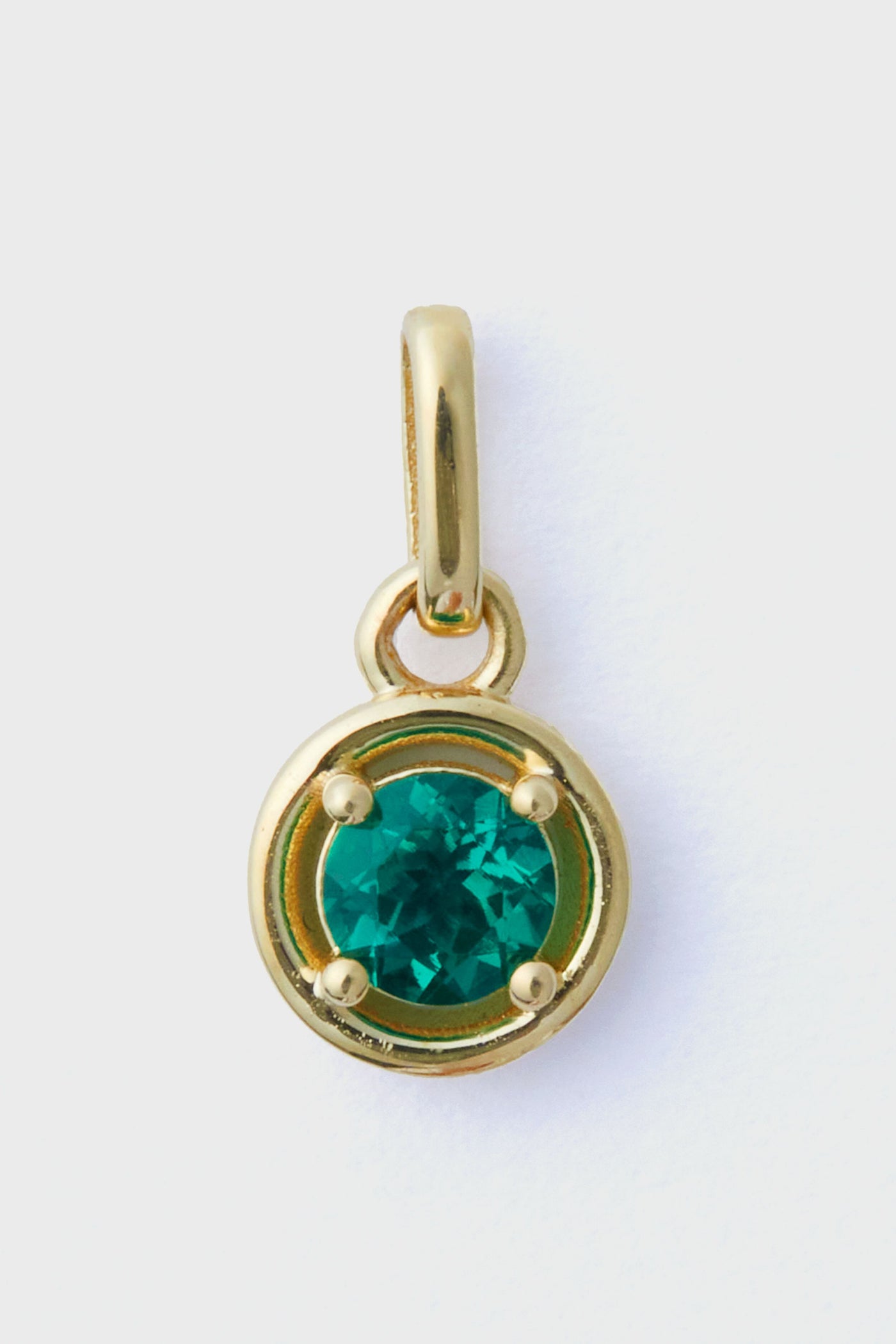 The Tuckernuck Fine Jewelry gold pendant features a round emerald charm at its center, crafted from 14k gold—an exquisite piece of luxury jewelry.