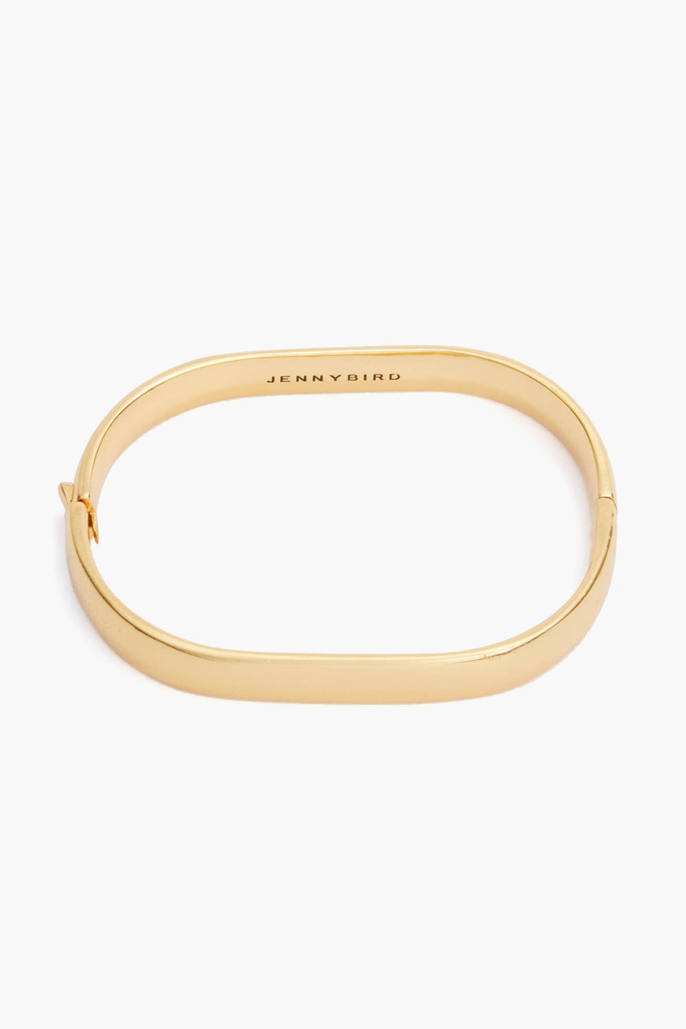 A vintage-inspired oval bangle from Jenny Bird, crafted from 14K gold-dipped brass with a smooth finish, hinged clasp, and "JENNY BIRD" engraved inside.